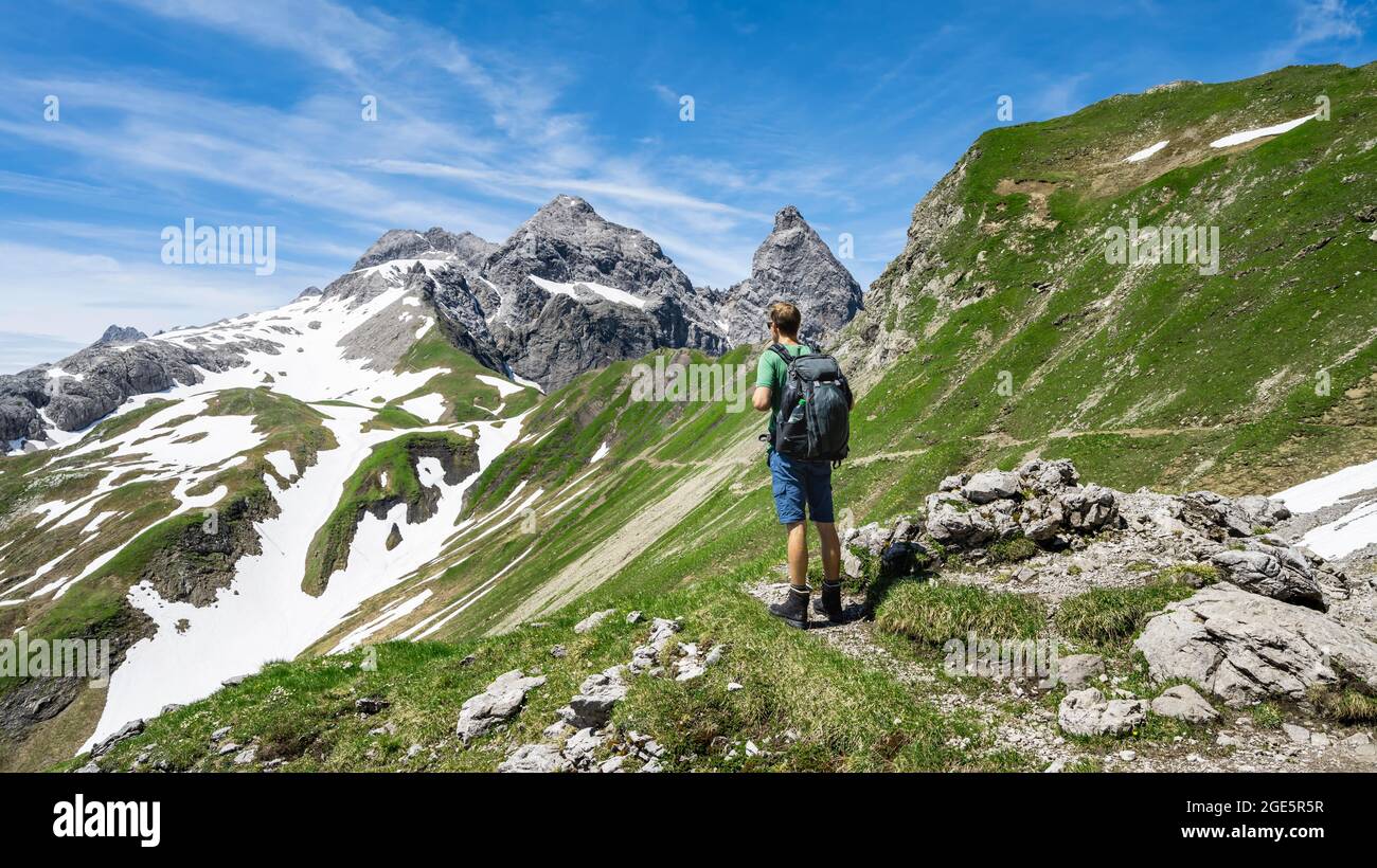 Wanderer auf Wanderweg, Blick in die Ferne, im Hintergrund alte Schneefelder und felsige Gipfel von Maedelegabel und Trettachspitze, Berg Stockfoto