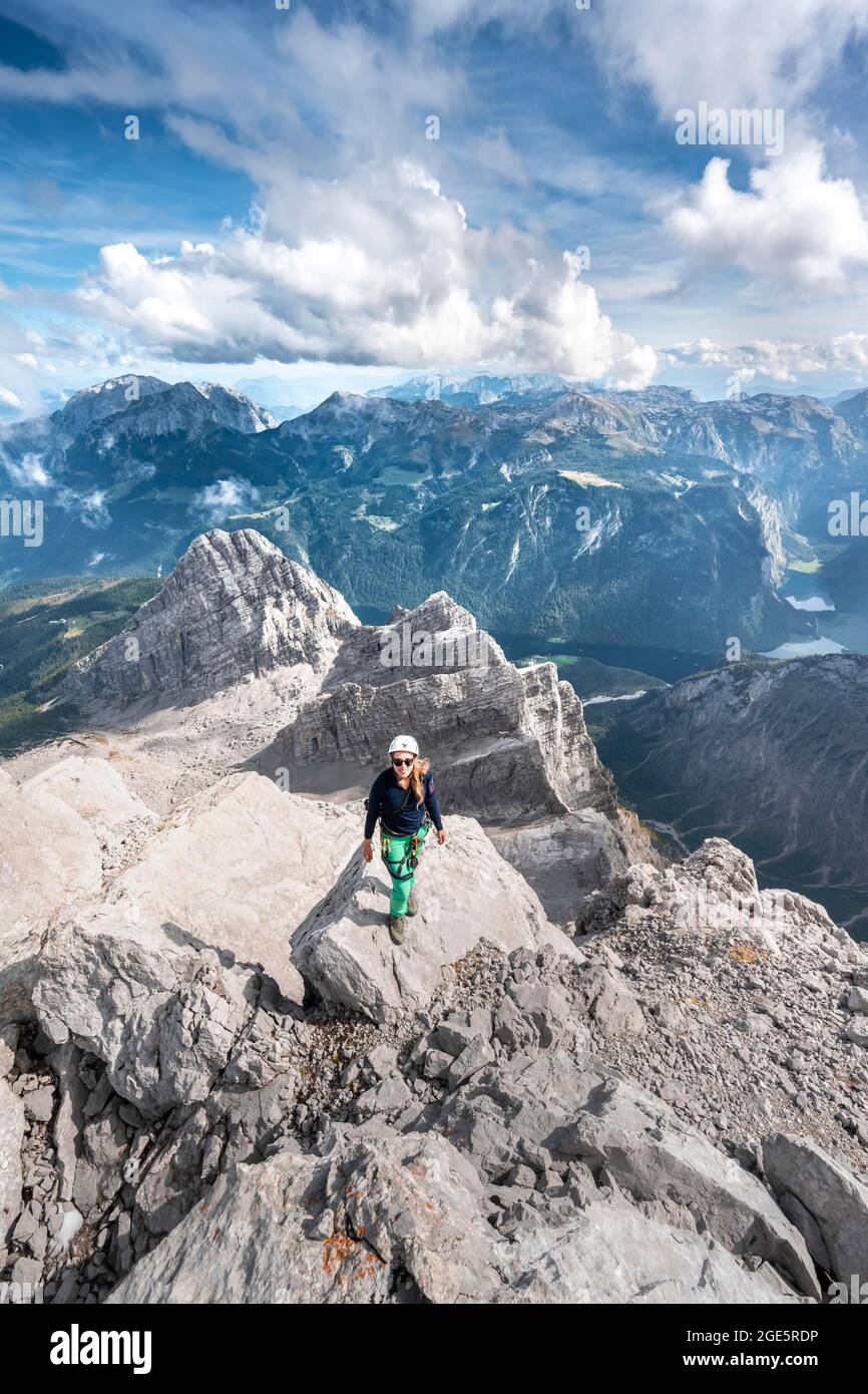 Wanderer mit Helm auf dem Gipfel des Watzmann Mittelgipfels, Blick über Berge, Königssee und Obersee, Wanderweg zum Watzmann, Watzmann Stockfoto