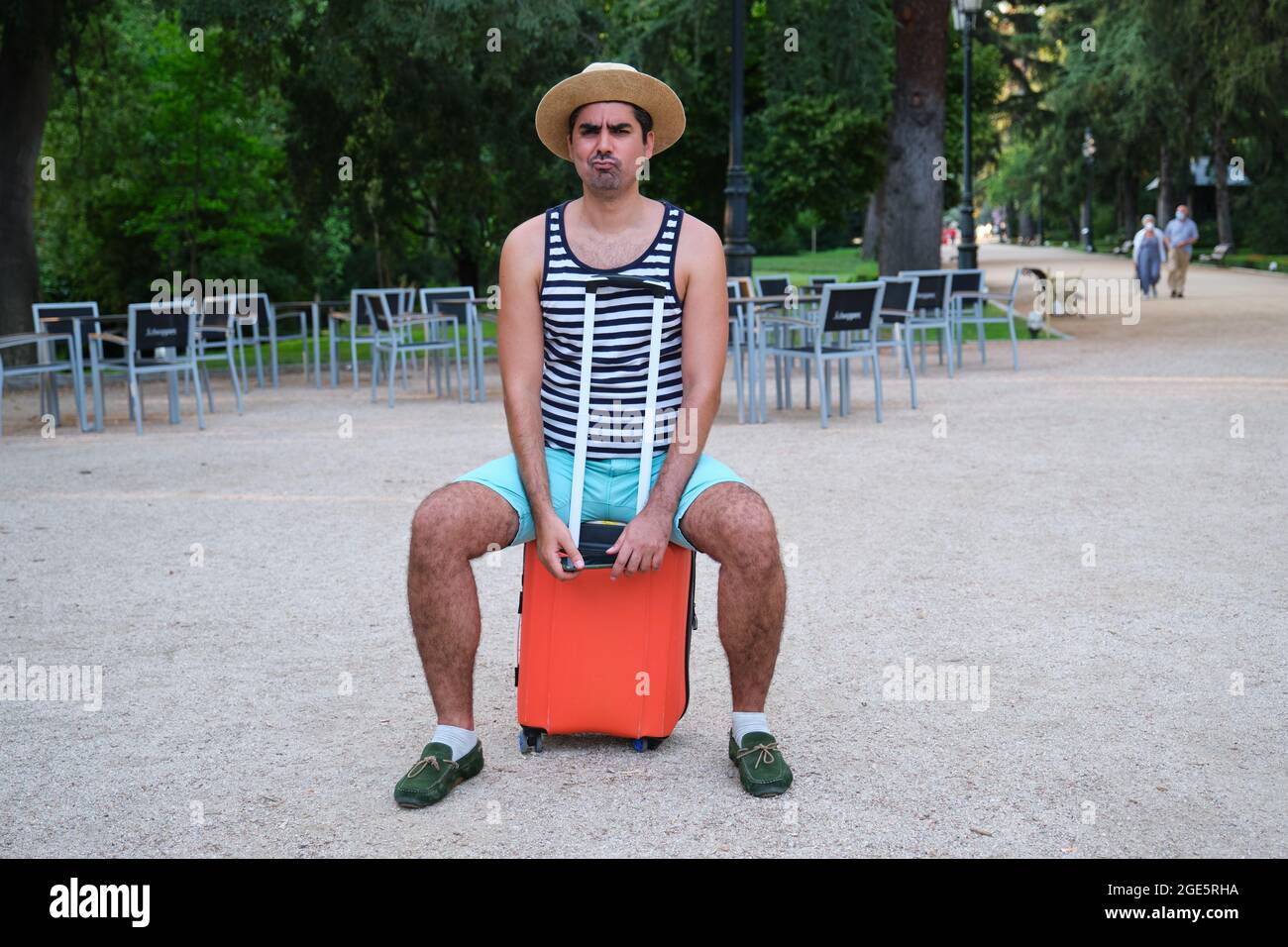 Tourist Mann mit einem verdächtigen Gesicht sitzt auf Koffer in einem Park. Stockfoto