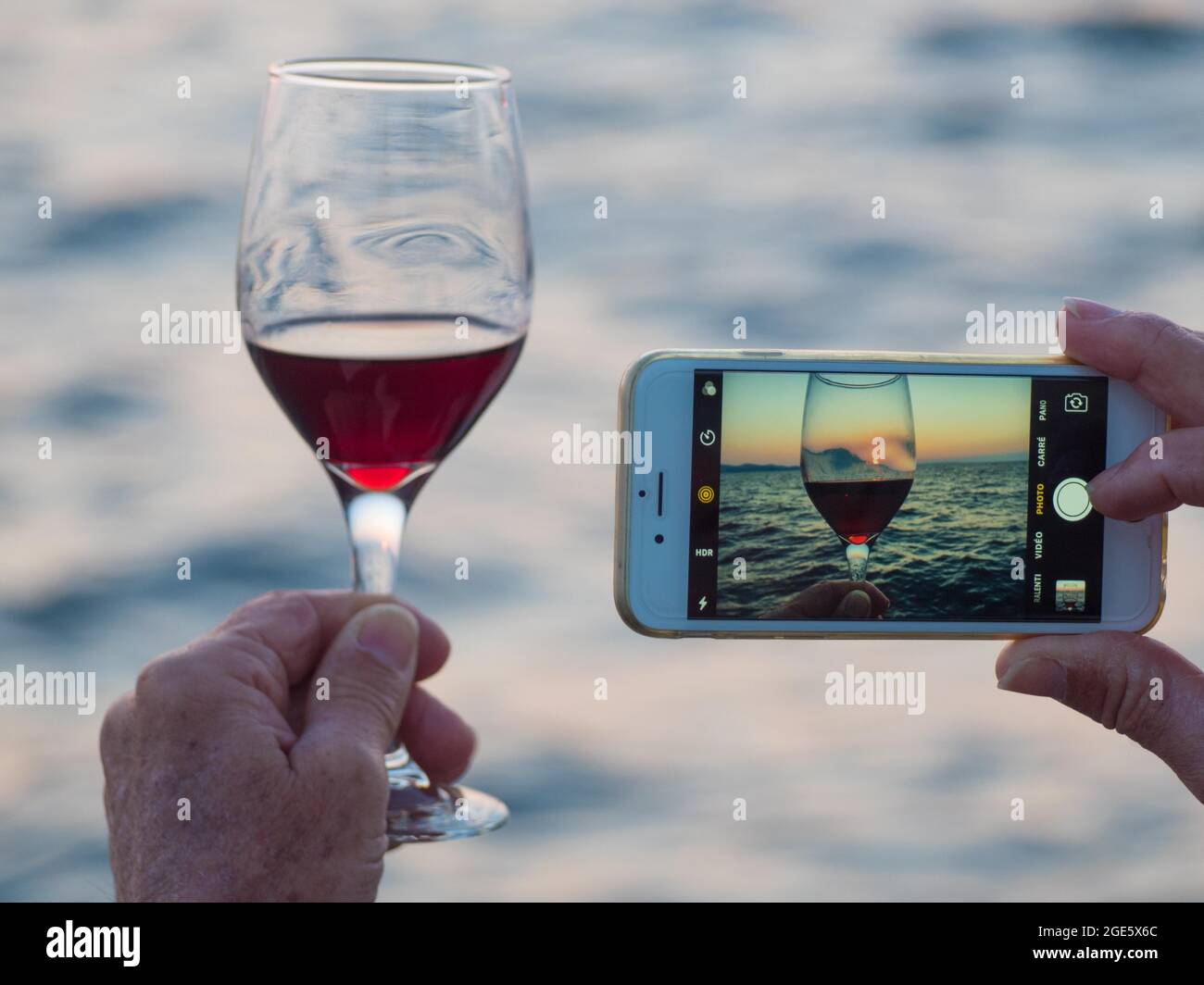 Tourist fotografieren Weinglas und Sonnenuntergang mit seinem Smartphone, Zadar, Dalmatien, Kroatien Stockfoto