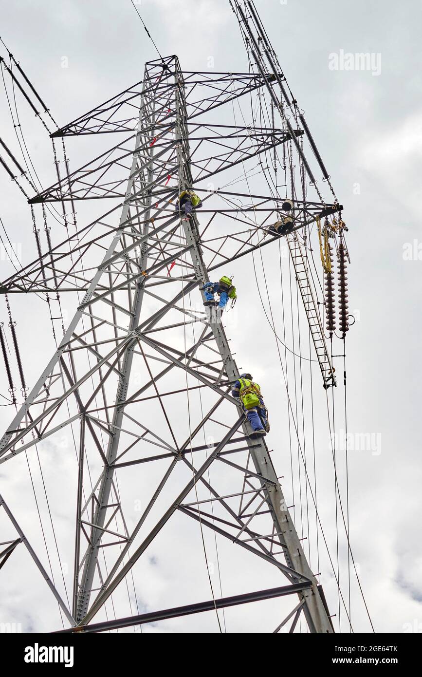 Männer, die in großer Höhe arbeiten und Strommasten sanieren, Nordengland, Großbritannien Stockfoto