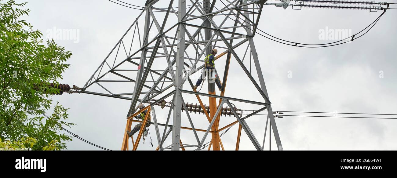Männer, die in großer Höhe arbeiten und Strommasten sanieren, Nordengland, Großbritannien Stockfoto