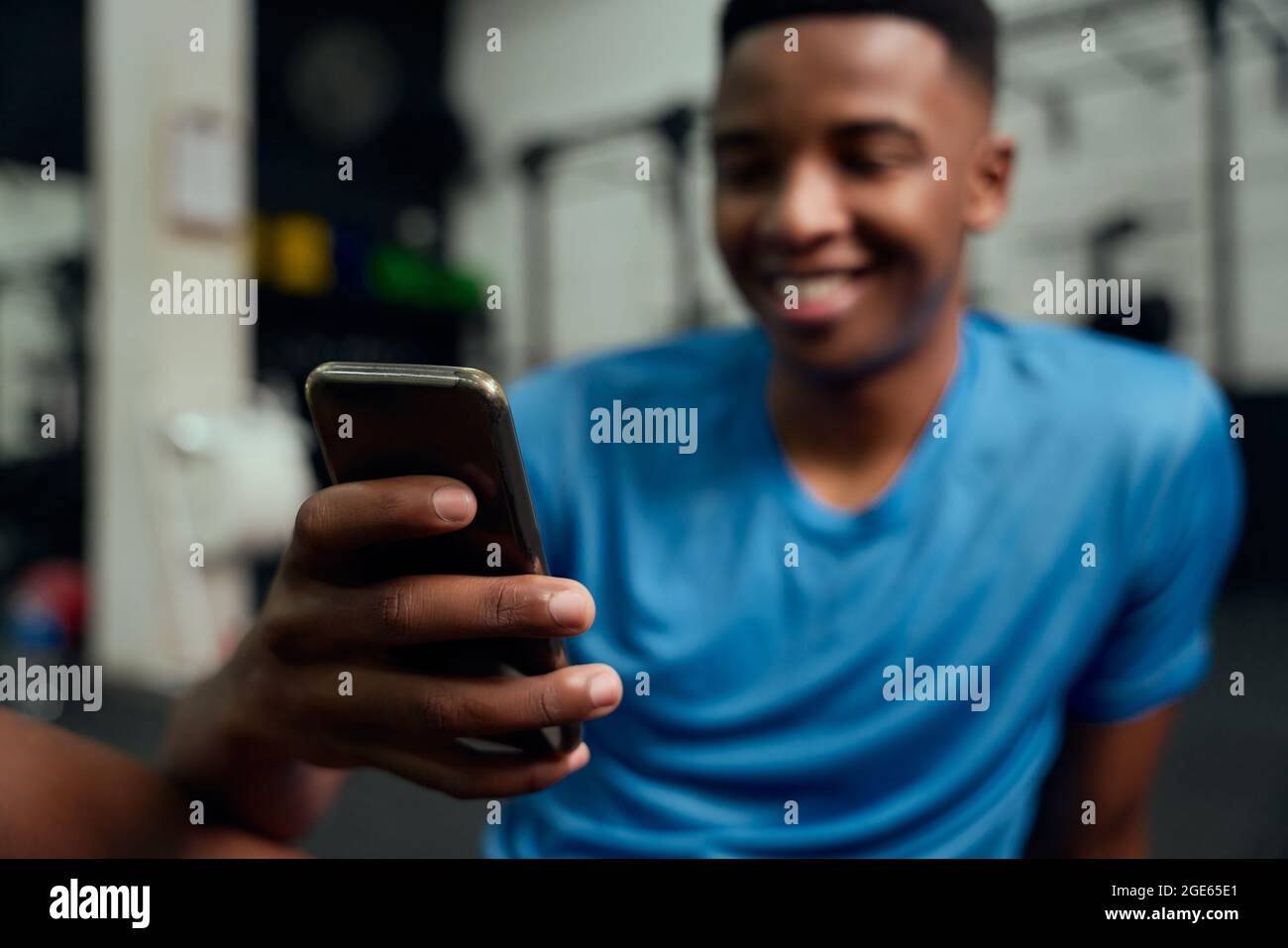 Afroamerikanischer Mann, der auf sein Telefon schaut. Nahaufnahme von männlichen Scrolling-Apps auf seinem Handy, während er sich im Fitnessstudio ausruhte. Hochwertige Fotos Stockfoto