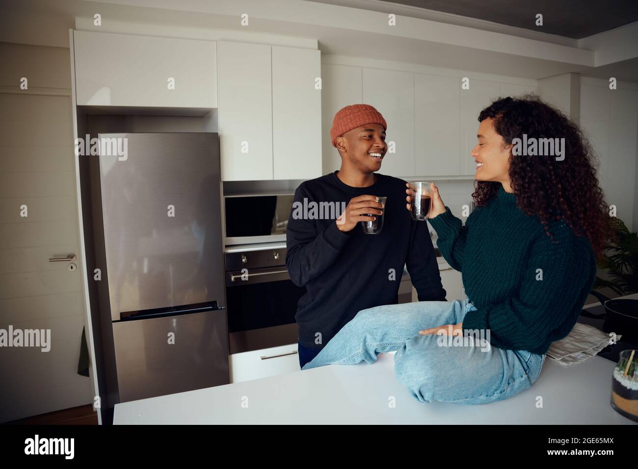 Glückliches, junges afroamerikanisches Paar, das Kaffee trinkt. Gemischtes Rennpaar schaut sich in der Küche zu Hause an. Hochwertige Fotos Stockfoto