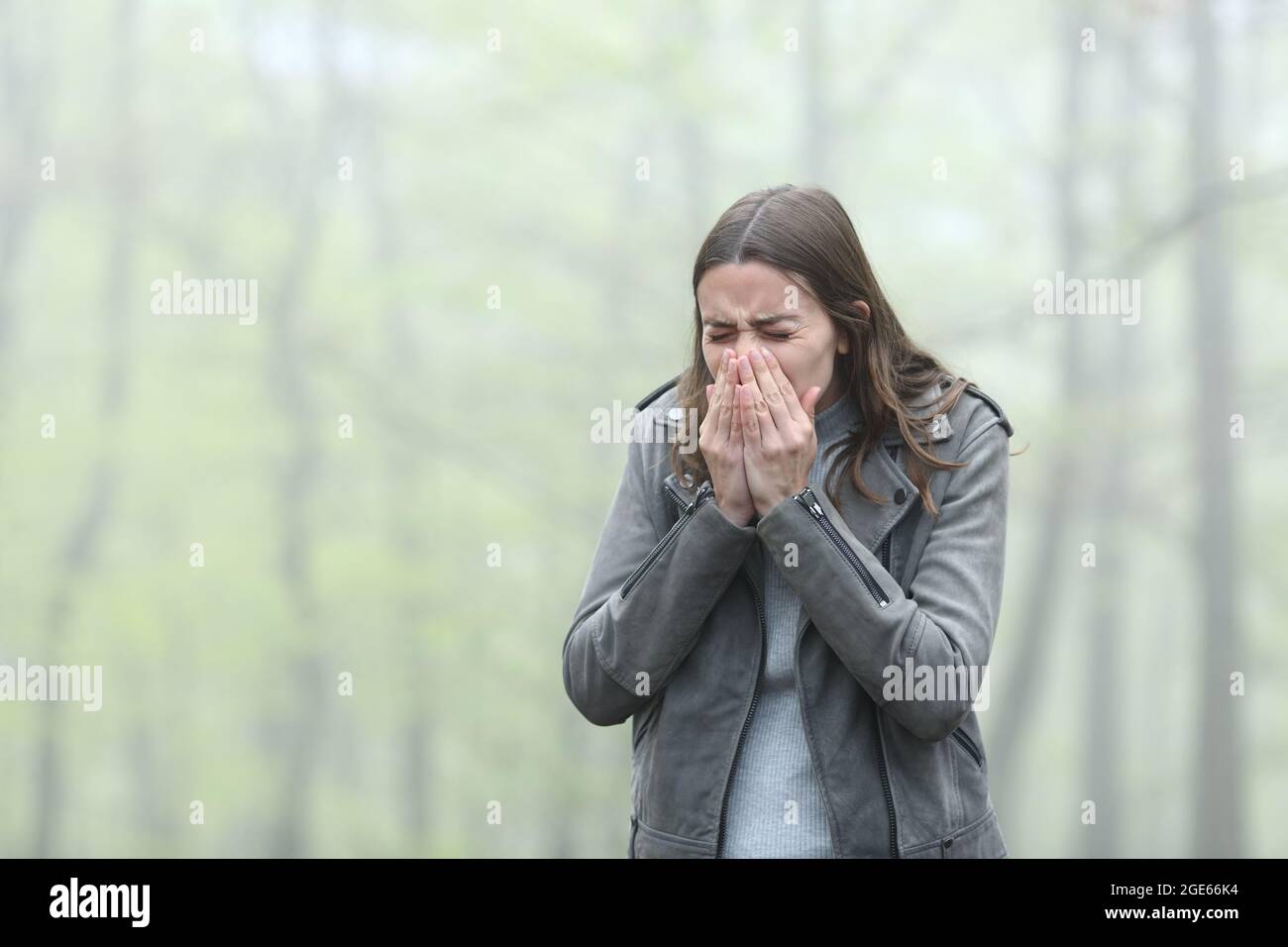 Gestresste Frau niest an einem kalten nebligen Tag in einem Park Stockfoto