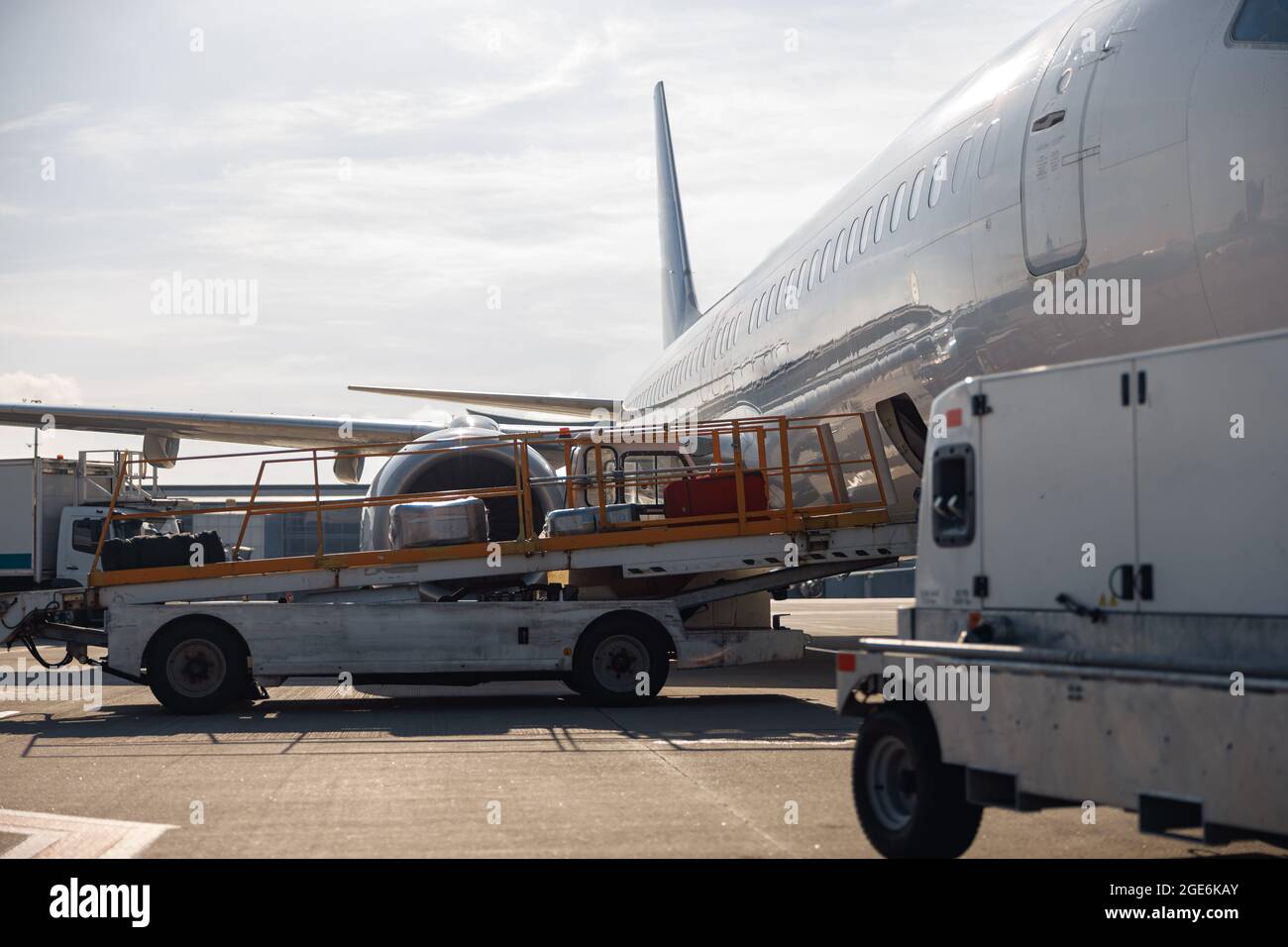 Gepäck auf einem Förderband, das tagsüber aus einem Flugzeug im Freien entladen wurde Stockfoto
