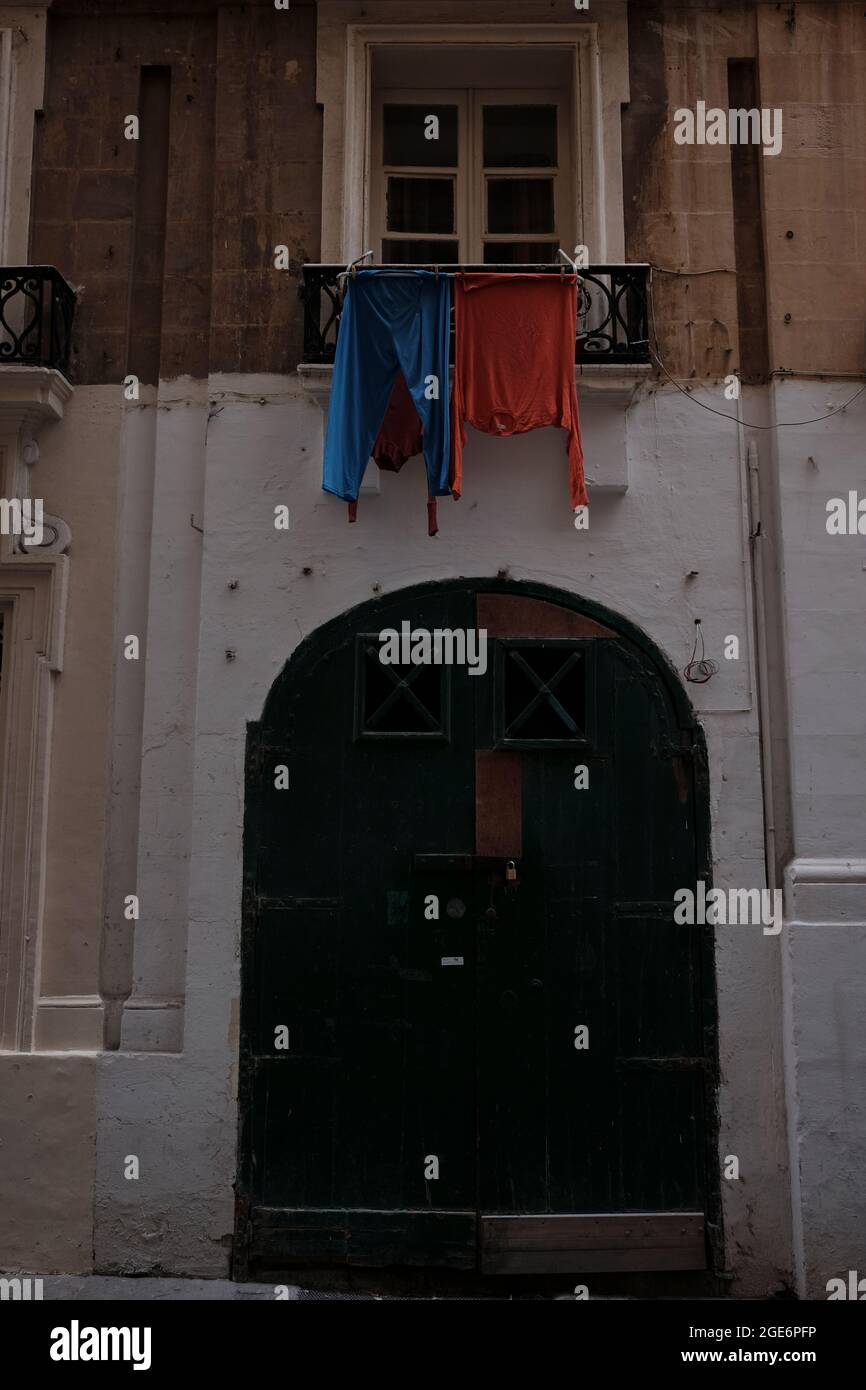 In den Straßen von Valletta werden rote und blaue Hemden zum Trocknen aufgehängt. Stockfoto