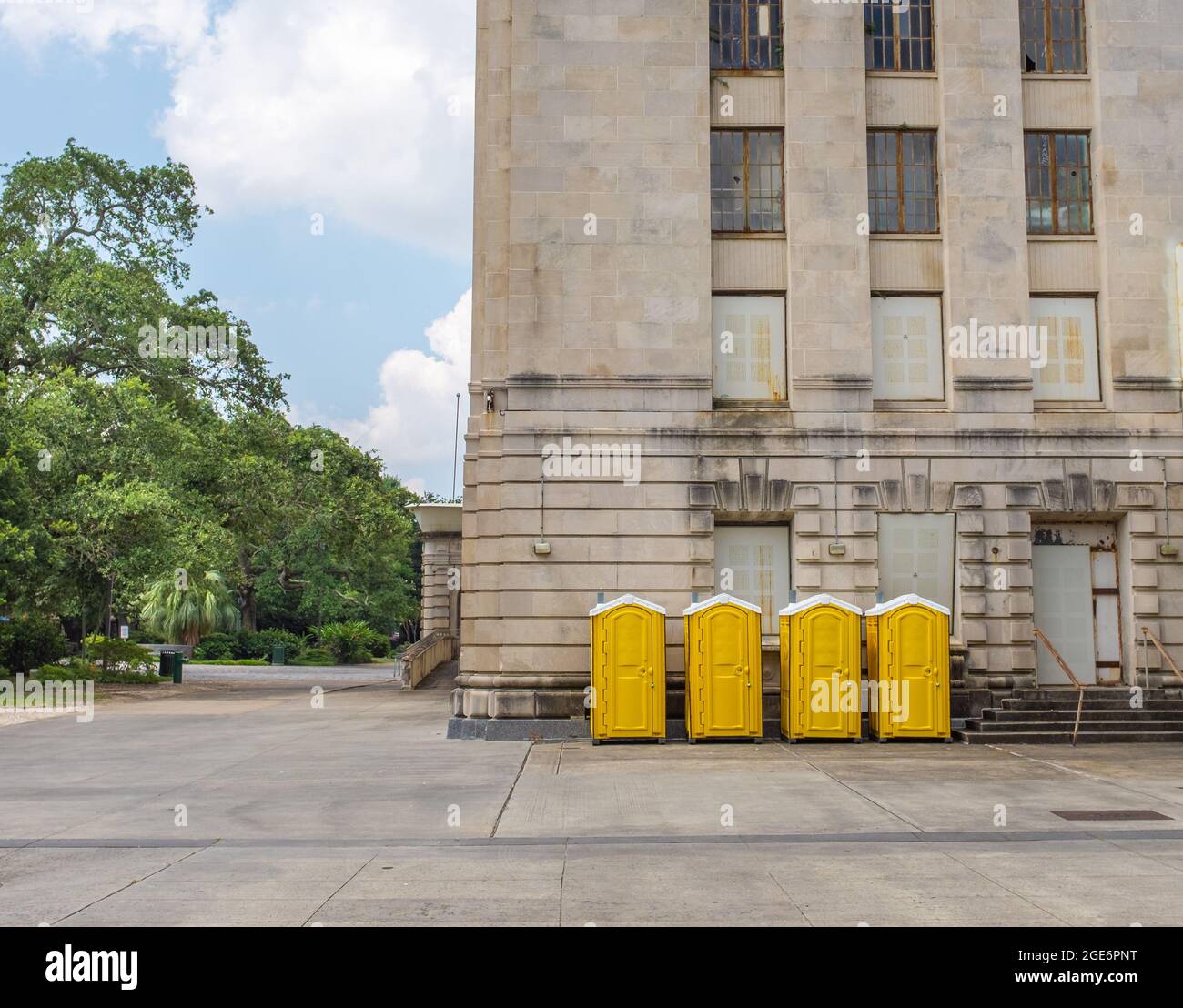 Vier gelbe tragbare Toiletten an der Seite des Gebäudes Stockfoto