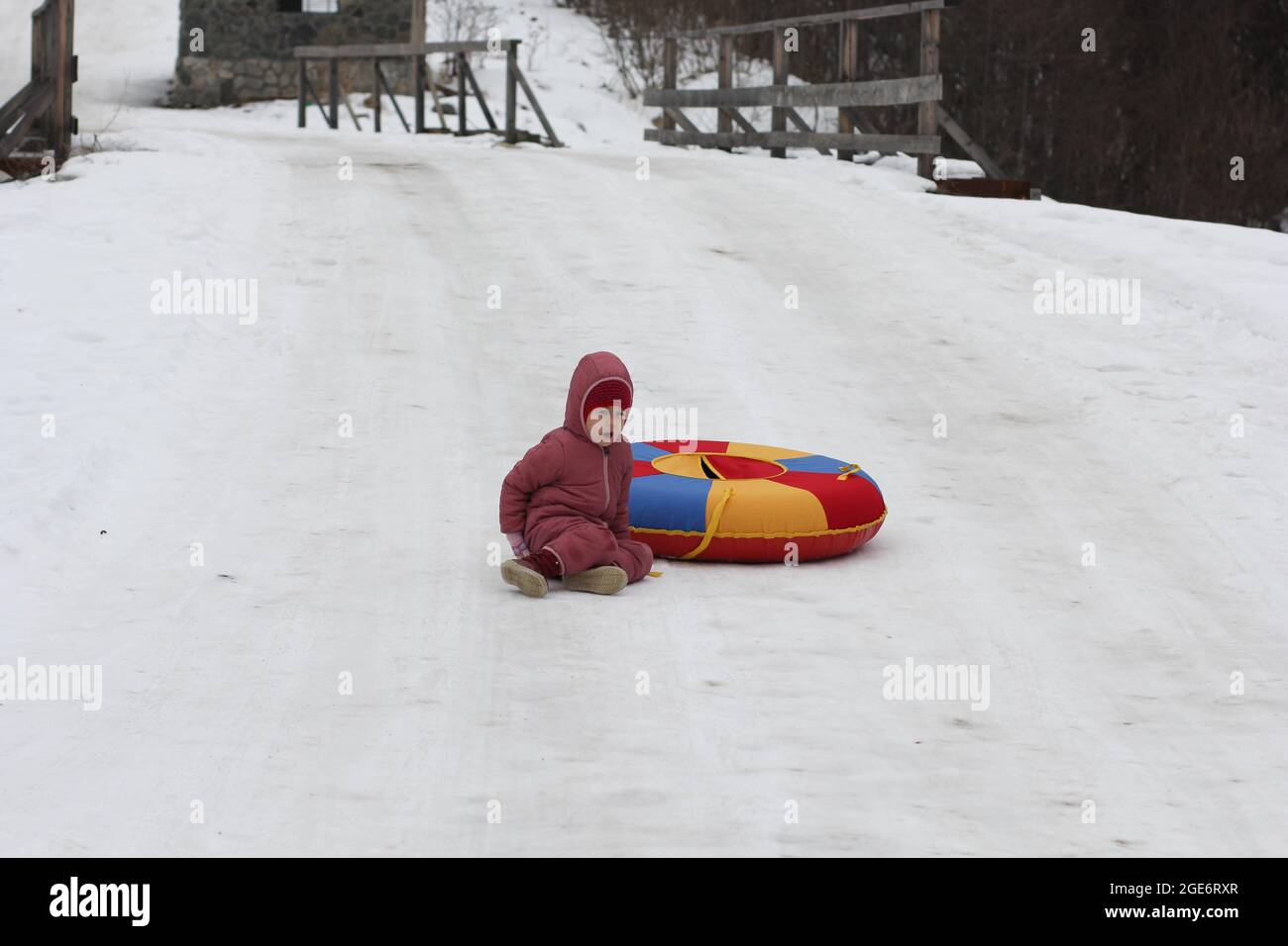Kaukasisches Kind im Alter von fünf Jahren, das im Winter während der Schlauchleitung auf einem Hügel aus dem Rohr fällt Stockfoto