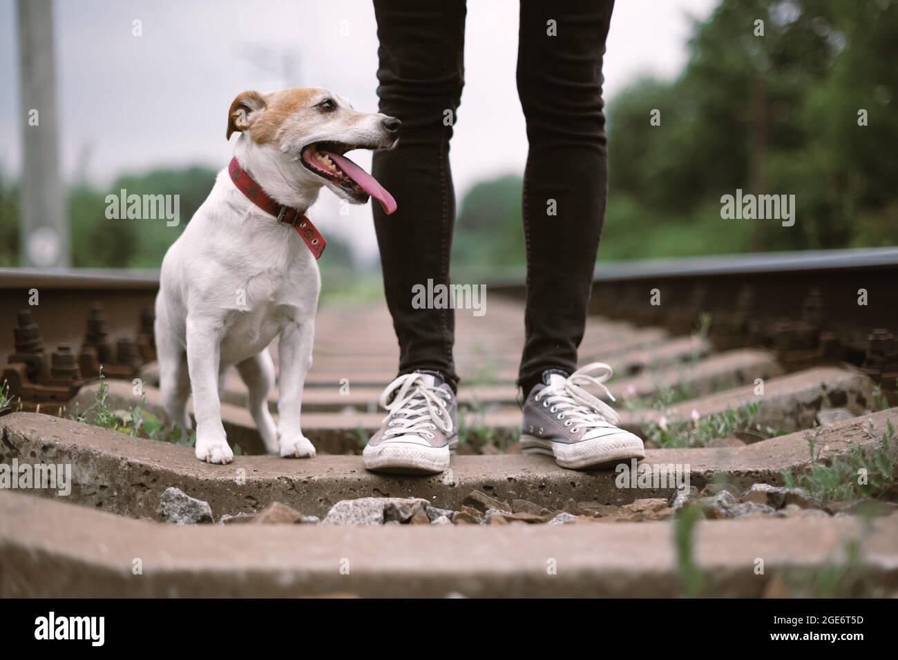 Hipster-Mann in schwarzer Jeans-Hose und grauen Sneakers auf der Bahn Stockfoto