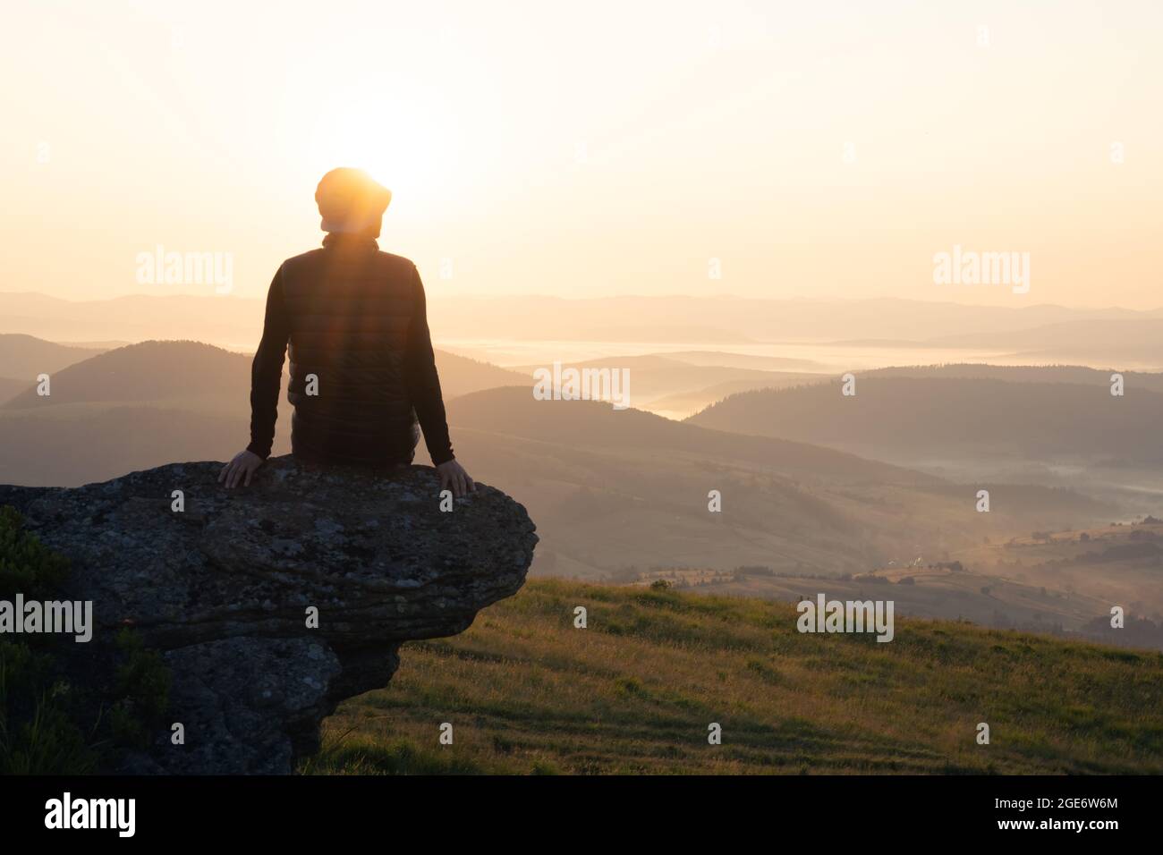 Allein Tourist am Rande des Berghügels gegen Die Kulisse eines unglaublichen Sonnenuntergangs Berglandschaft Stockfoto