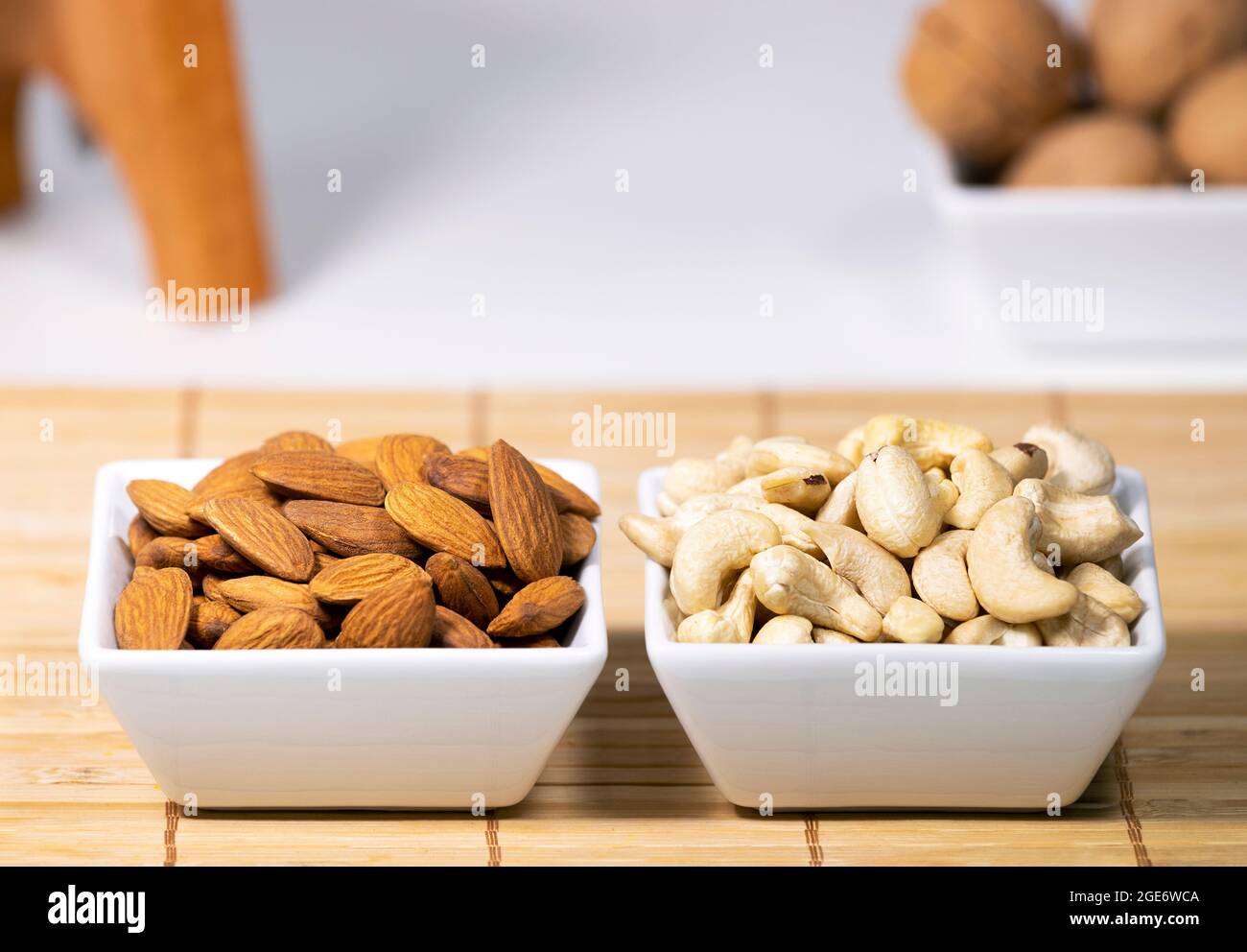 Mischung aus Nüssen, Mandel, Cashew, Wallnut in weißen Keramikschalen auf Holzständer, gesunde Snacks, Diät Stockfoto