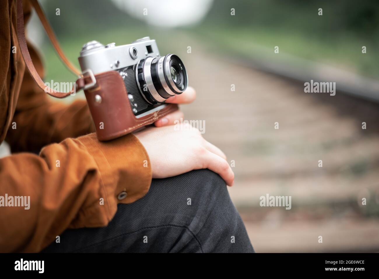 Fotograf in brauner Jacke, der die Retro-Kamera aus der Nähe in die Hände nimmt Stockfoto