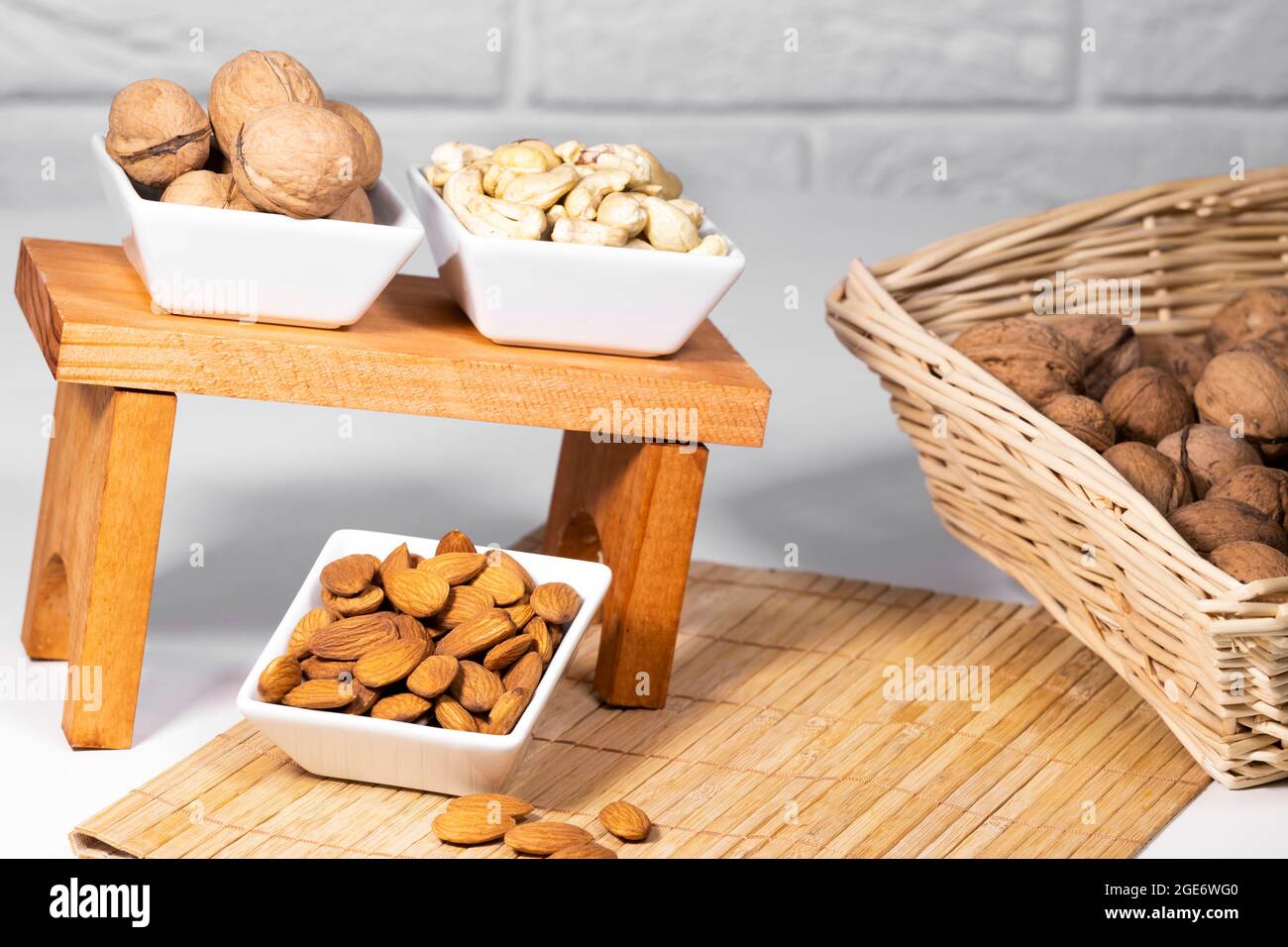 Mischung aus Nüssen, Mandel, Cashew, Wallnut in weißen Keramikschalen auf Holzständer, gesunde Snacks, Diät Stockfoto