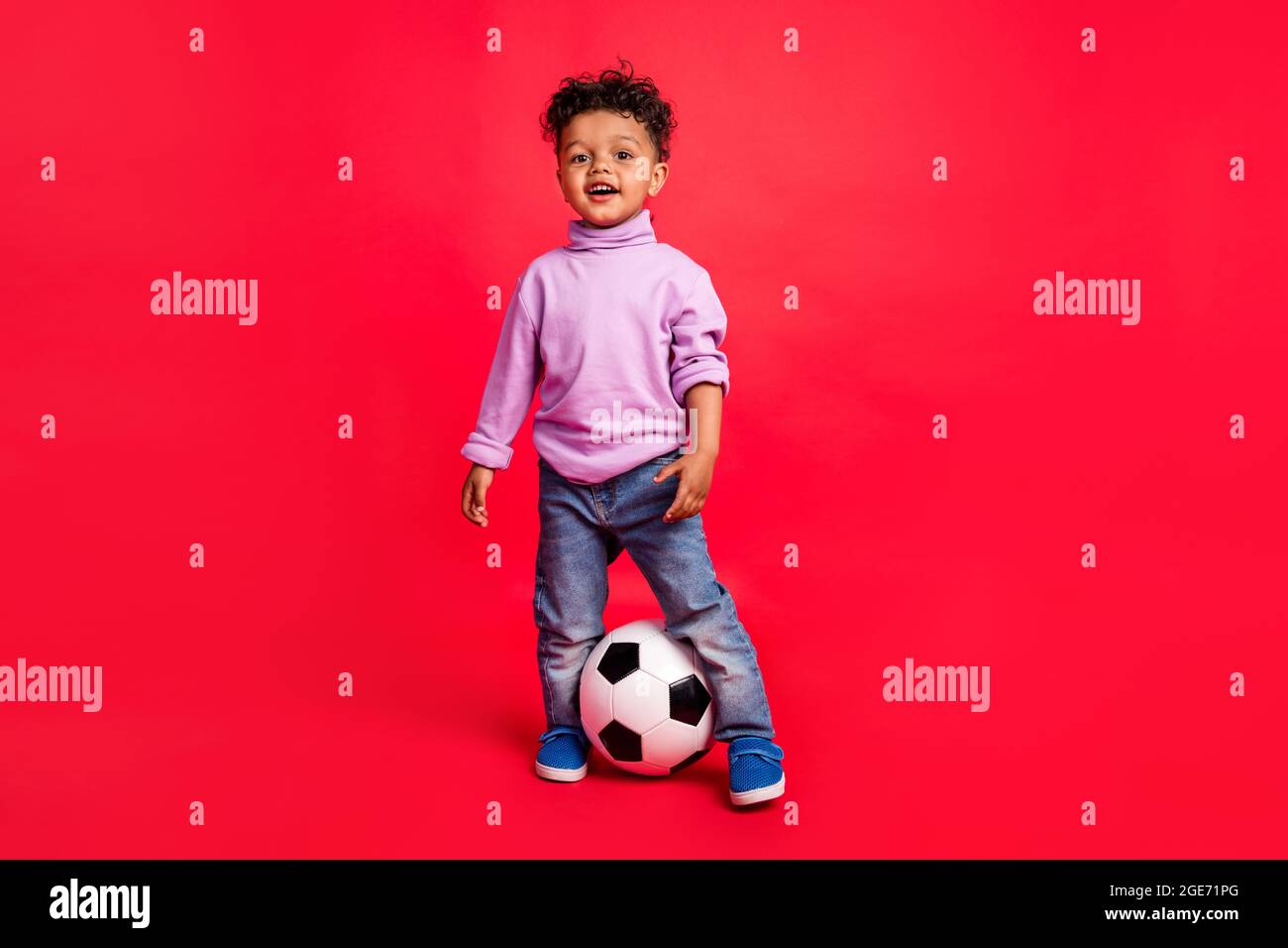 In voller Länge Körpergröße Ansicht der attraktiven fröhlich preteen Kerl Fußballspiel Pass isoliert über hellen roten Hintergrund Stockfoto