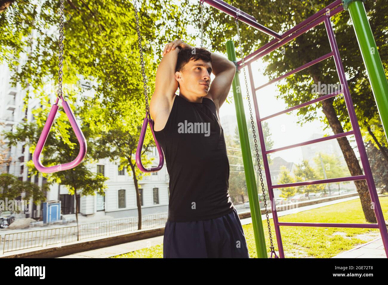Ein junger, hübscher Kaukasianer, der an einem hellen Sommertag auf dem Sportplatz im Freien trainiert. Stockfoto