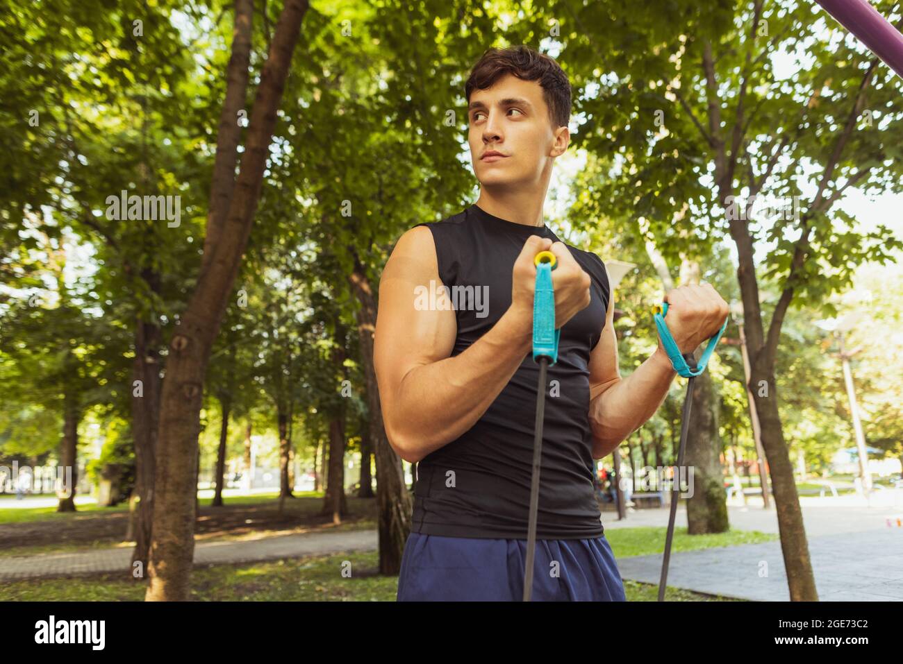 Ein junger, hübscher Kaukasusmann in Sportkleidung, der an einem hellen Sommertag mit Seil im Freien springt. Stockfoto