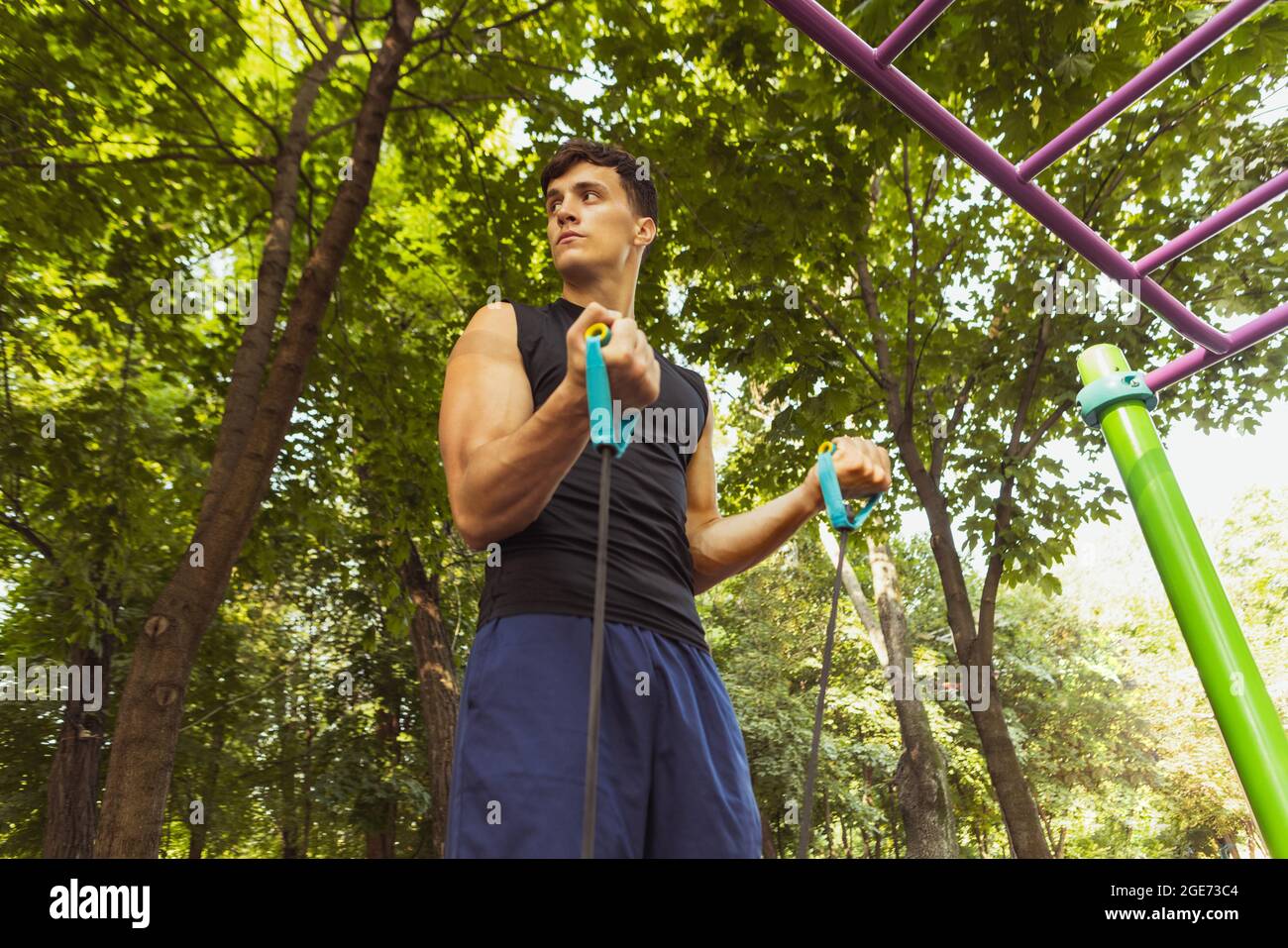 Ein junger, hübscher Kaukasusmann in Sportkleidung, der an einem hellen Sommertag mit Seil im Freien springt. Stockfoto