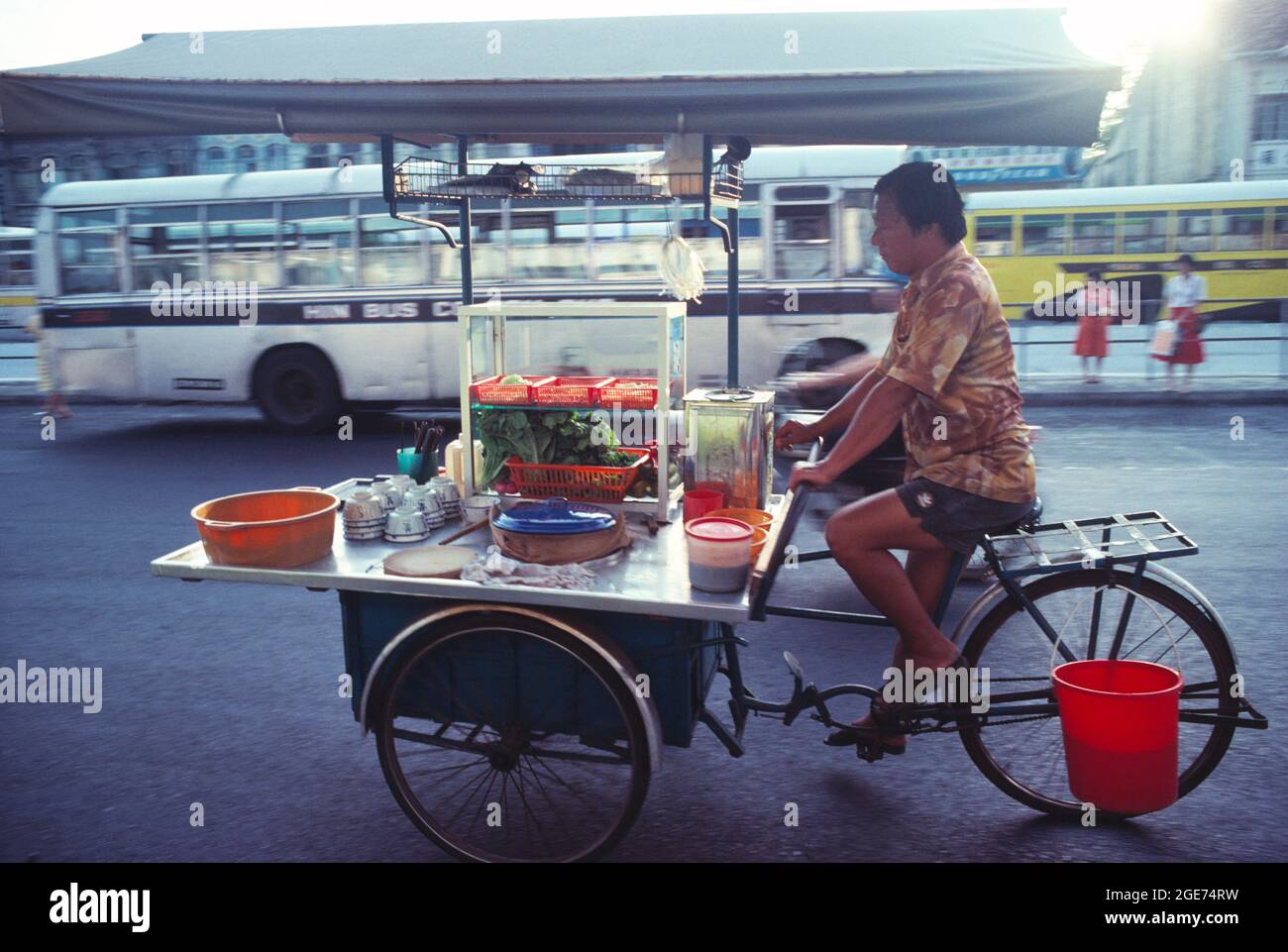 Malaysia. Penang. Ein Einheimischer tritt mit seinem Dreirad an den Lebensmittelautomaten. Stockfoto