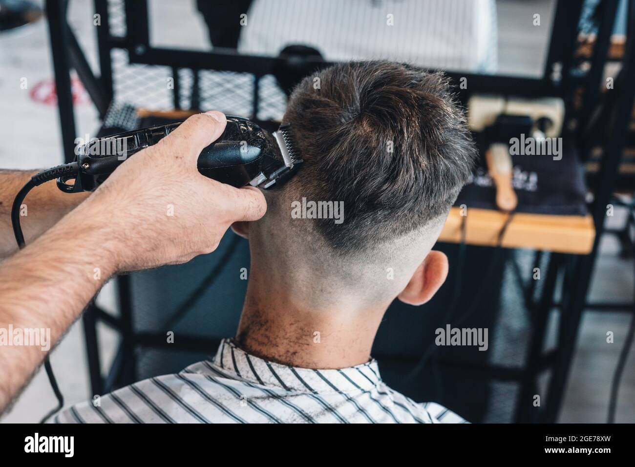 Professionelle Frisur und Styling für Herren in einem Friseursalon oder Friseursalon. Barber gibt einem Teenager einen trendigen Haarschnitt. Nahaufnahme. haarpflege Stockfoto