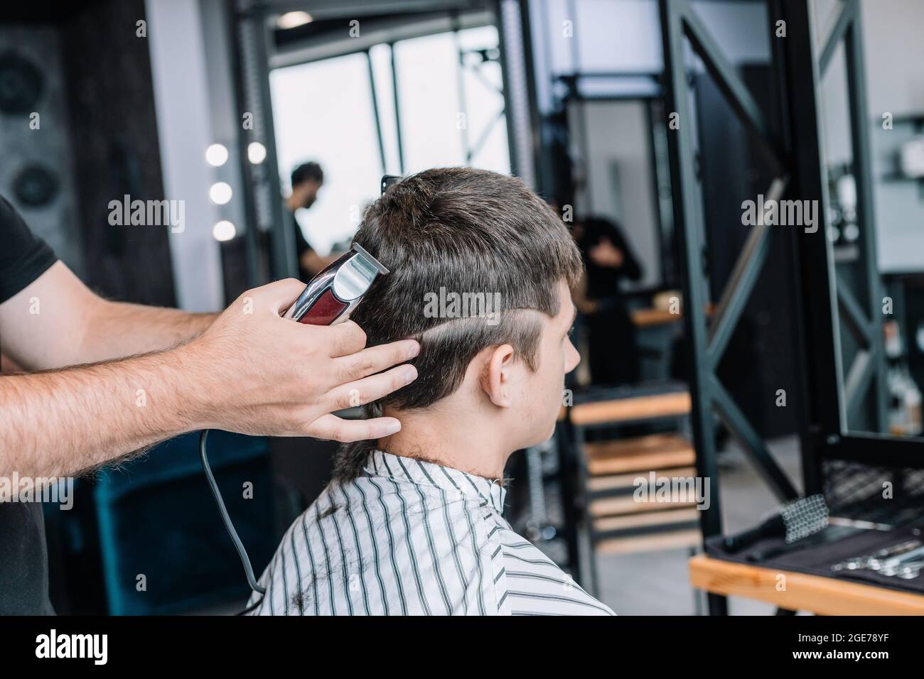 Barber macht einen modischen stilvollen Haarschnitt zu einem jungen Mann. Barbershop. Professionelle Männer Rasur und Haarschnitt, Haarpflege. Stockfoto