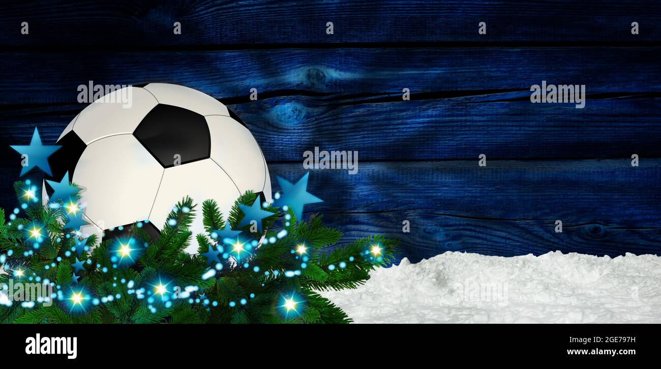 Fußball-weihnachtskugel im Schnee mit weihnachtsdekoration und Tannenzweig. Blauer Holzhintergrund. Weihnachtsgrüße Stockfoto