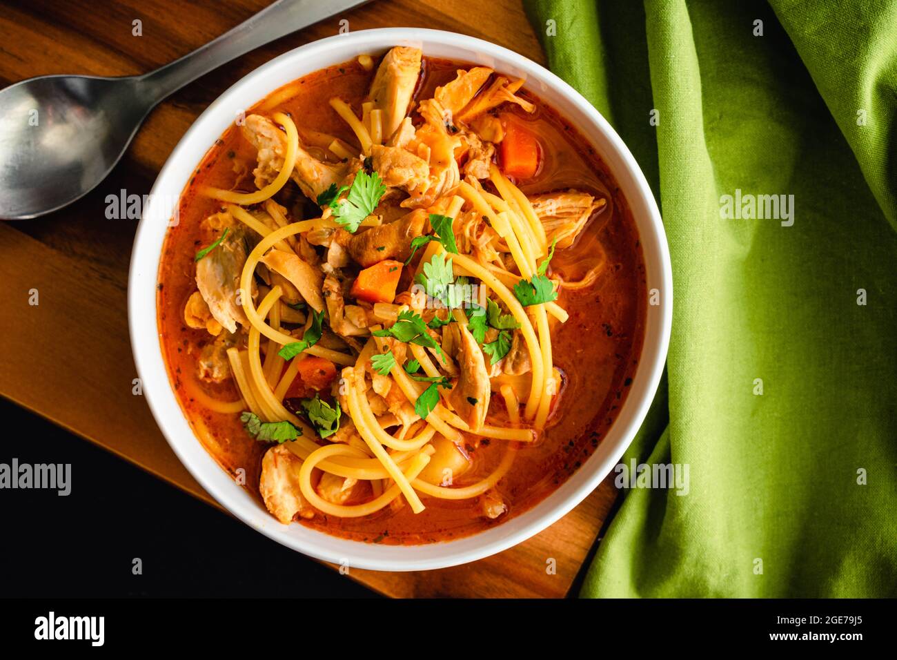 Kubanische Hühnchen-Nudelsuppe garniert mit Cilantro: Schüssel Hühnchen-Nudelsuppe in einer Tomatenbrühe Stockfoto