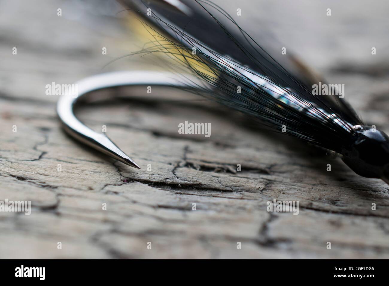 Glänzende Lachsfischfliege mit gelbem Blitz auf einer Holzoberfläche Stockfoto