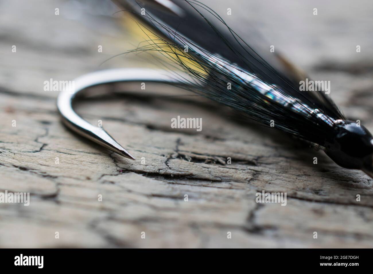 Glänzende Lachsfischfliege mit gelbem Blitz auf einer Holzoberfläche Stockfoto