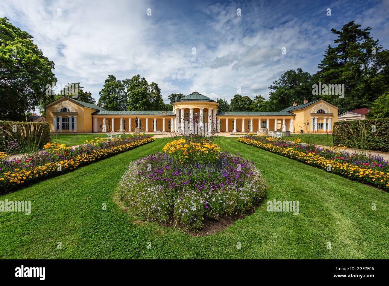 Marienbad, Tschechische Republik - August 12 2021: Blick auf den gelben Ferdinand-Frühlingspavillon mit Säulen, bunten Blumen und grünem Rasen. Sommertag. Stockfoto