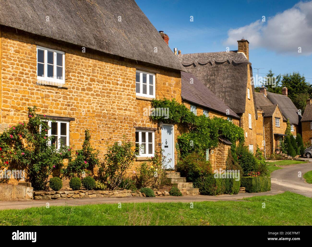 Großbritannien, England, Oxfordshire, Wroxton, Main Street, Hübsche reetgedeckte Cotswold-Hütten um das Dorfgrün herum Stockfoto