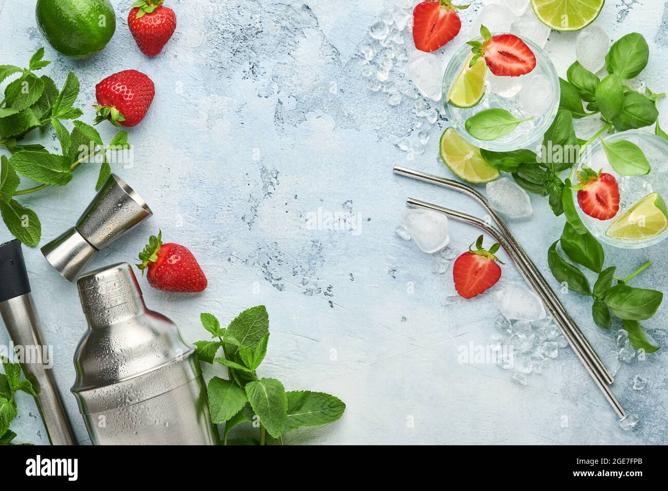 Lebensmittel Frische Zutaten für die Herstellung von Limonade, infundiert entgiftendes Wasser oder Cocktail. Erdbeeren, Limette, Minze, Basilikum, Eiswürfel und Shaker auf blauem oder grauem Sto Stockfoto