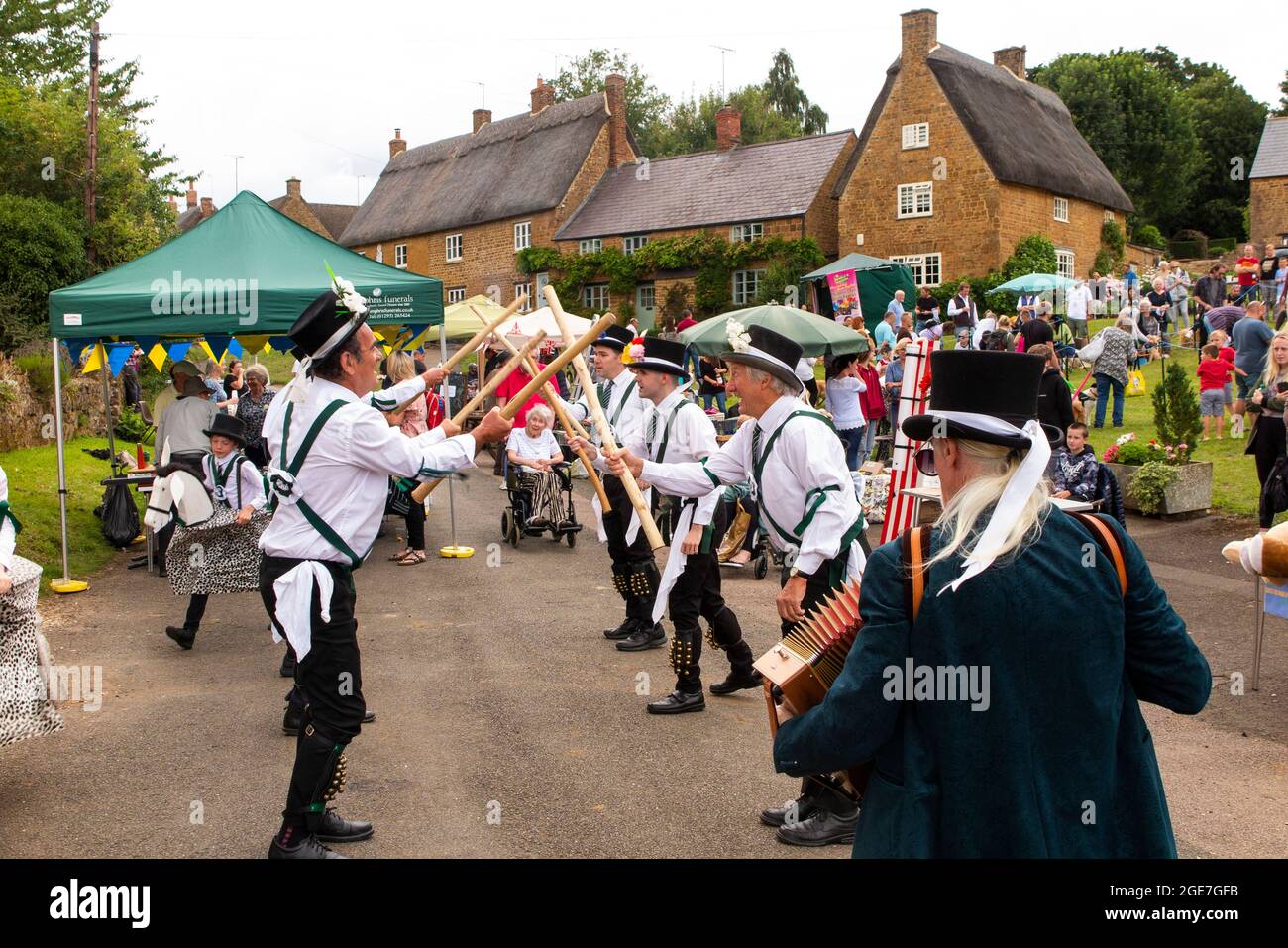 Großbritannien, England, Oxfordshire, Wroxton, jährliches Kirchenfest im Gange, Morris-Tänzer mit Stöcken auf der Main Street, am Rande des Dorfgrüns Stockfoto