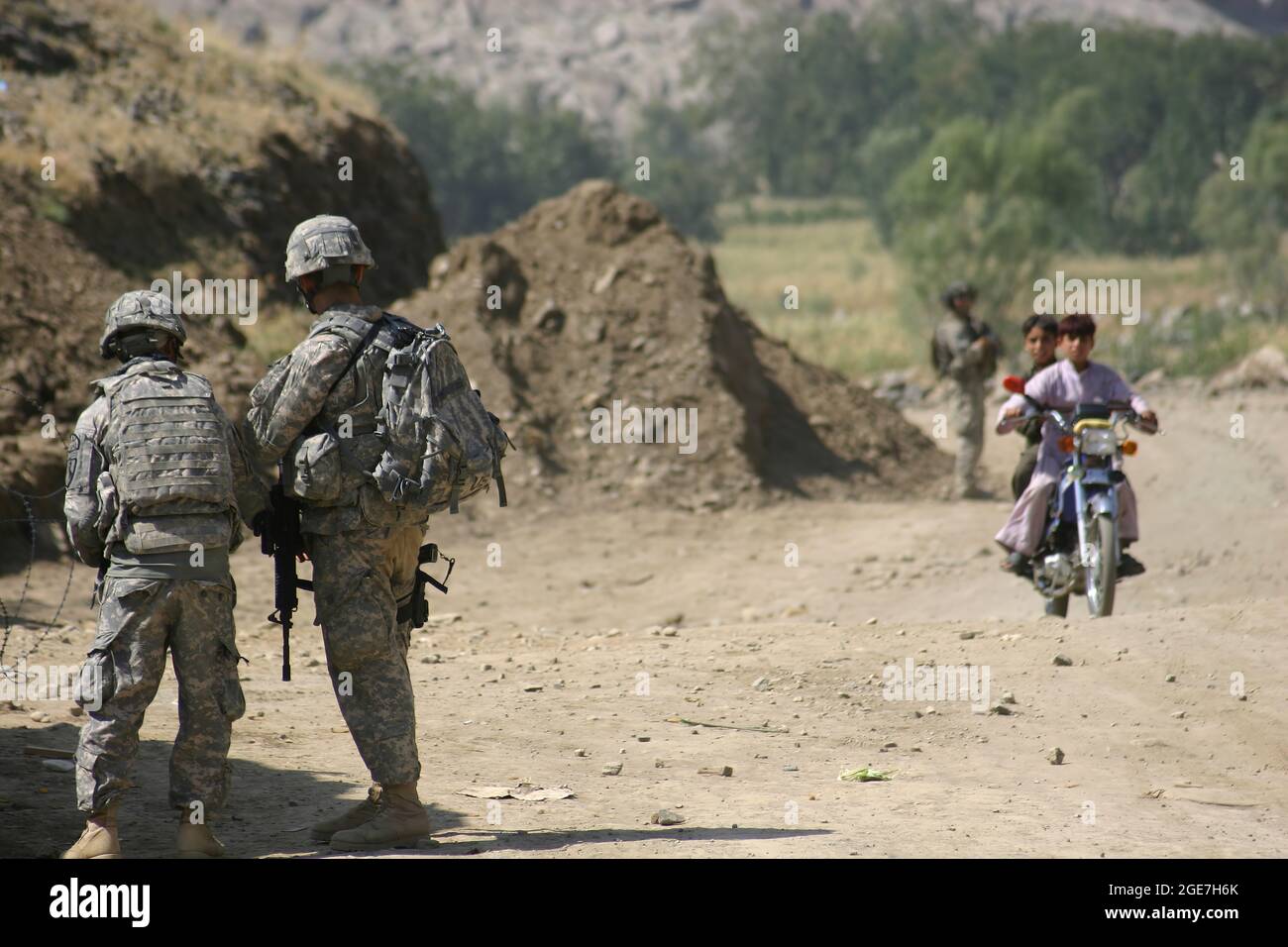 US-Kampftruppen in Afghanistan - zwei Soldaten, die 1-221 Kavalleriegeschwader, Nevada Nationalgarde, zugewiesen sind, beobachten zwei afghanische Jungen auf einem Fahrrad, wie sie einen Militärkontrollpunkt vor dem Kampfposten Najil in der Provinz Laghman, Afghanistan, passieren 29. September 2009. Die 1-221 verbrachten während der serge 2009 neun Monate in Afghanistan, die der Task Force Mountain Warrior angehängt waren. (USA Army Photo von SPC. Walter H. Lowell) Stockfoto