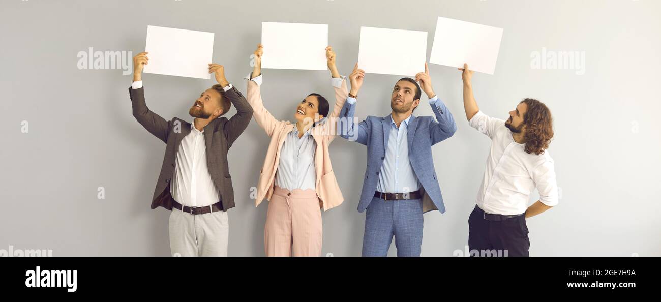 Eine Gruppe glücklicher Geschäftsleute, die im Studio stehen und weiße Mockup-Banner halten Stockfoto