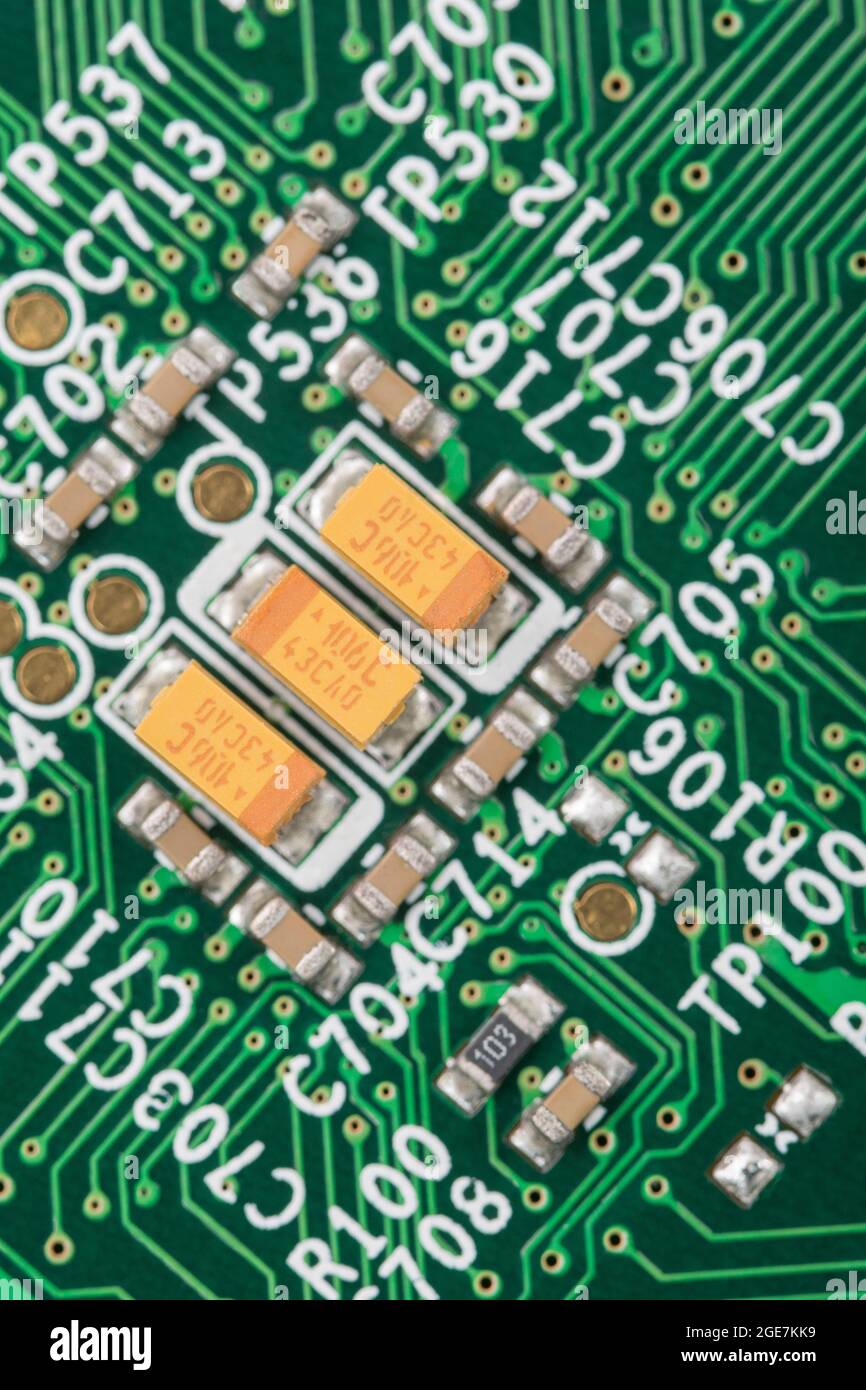 Seltene Erden-Tantaloxid-SMD-/SM-Kondensatoren auf hellgrüner leiterplatte + viele Verbindungsdrähte und Durchgangslöcher von Komponenten. Keine Marken-ID Stockfoto