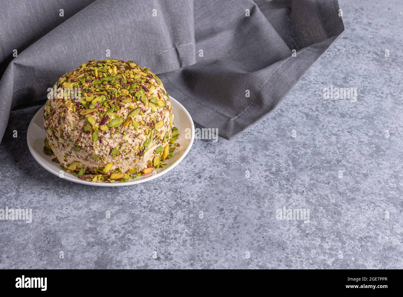 Sesamhalva mit Pistazien-Nüssen auf grauem Hintergrund mit grauer Leinenserviette an der Seite und Kopierraum. Türkisches Vergnügen. Traditionelle süsse aus dem Nahen Osten Stockfoto