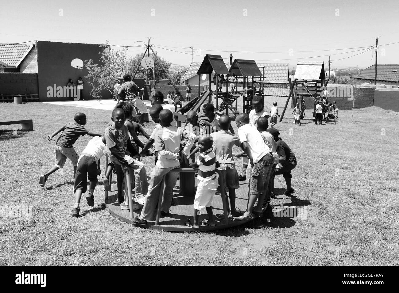 JOHANNESBURG, SÜDAFRIKA - 05. Jan 2021: Afrikanische Kinder, die fröhlich spielen, gehen auf einem öffentlichen Spielplatz in einer Graustufe herum und andere Parkgeräte Stockfoto