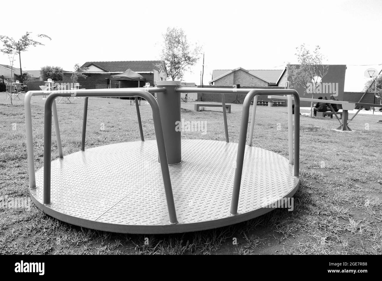 JOHANNESBURG, SÜDAFRIKA - 05. Jan 2021: Eine Graustufe eines leeren Fröhlichen geht um und andere Park-Ausrüstung auf einem lokalen öffentlichen Spielplatz Stockfoto