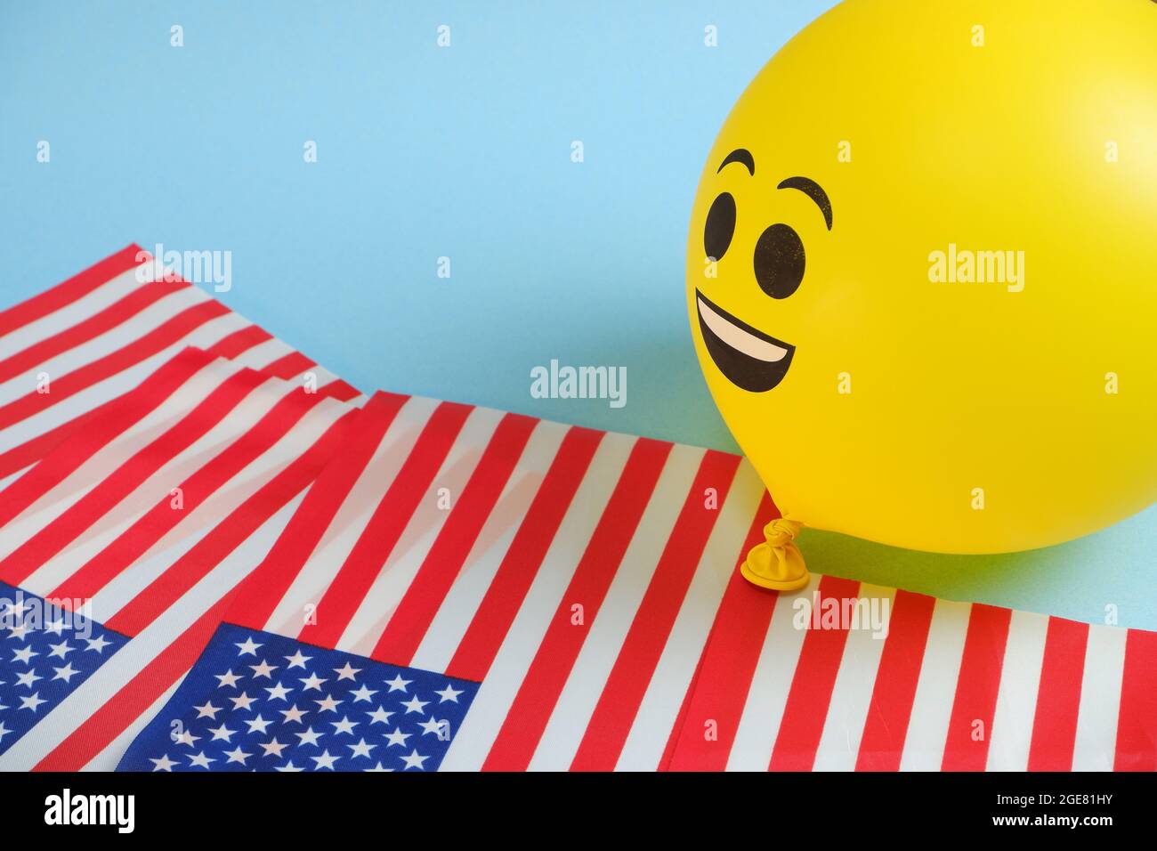 Gelbe Emoji-Ballons mit amerikanischen Flaggen auf blauem Hintergrund. Stockfoto
