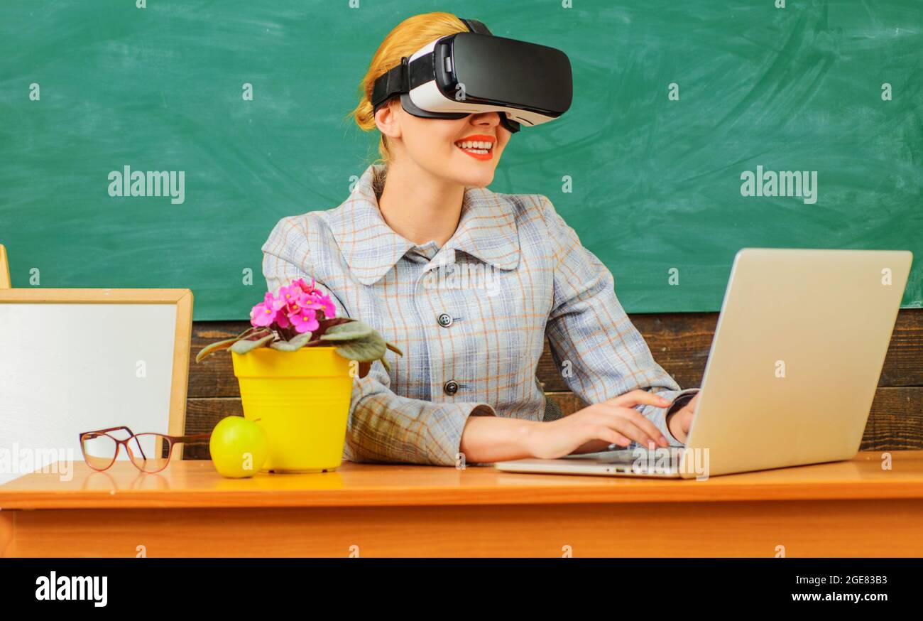 Glücklicher Lehrer im Klassenzimmer. Lächelnder Lehrer mit Laptop in vr-Headset. Digitale Bildung. Moderne Technologien in der intelligenten Schule. Stockfoto