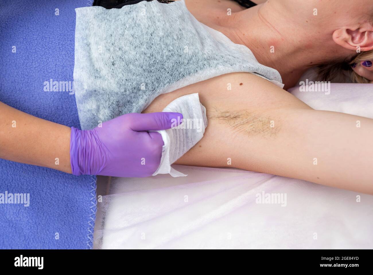 Der Kosmetologe bereitet in einem Spa-Salon die Achselhöhlen des Mädchens für die Enthaarung vor Stockfoto
