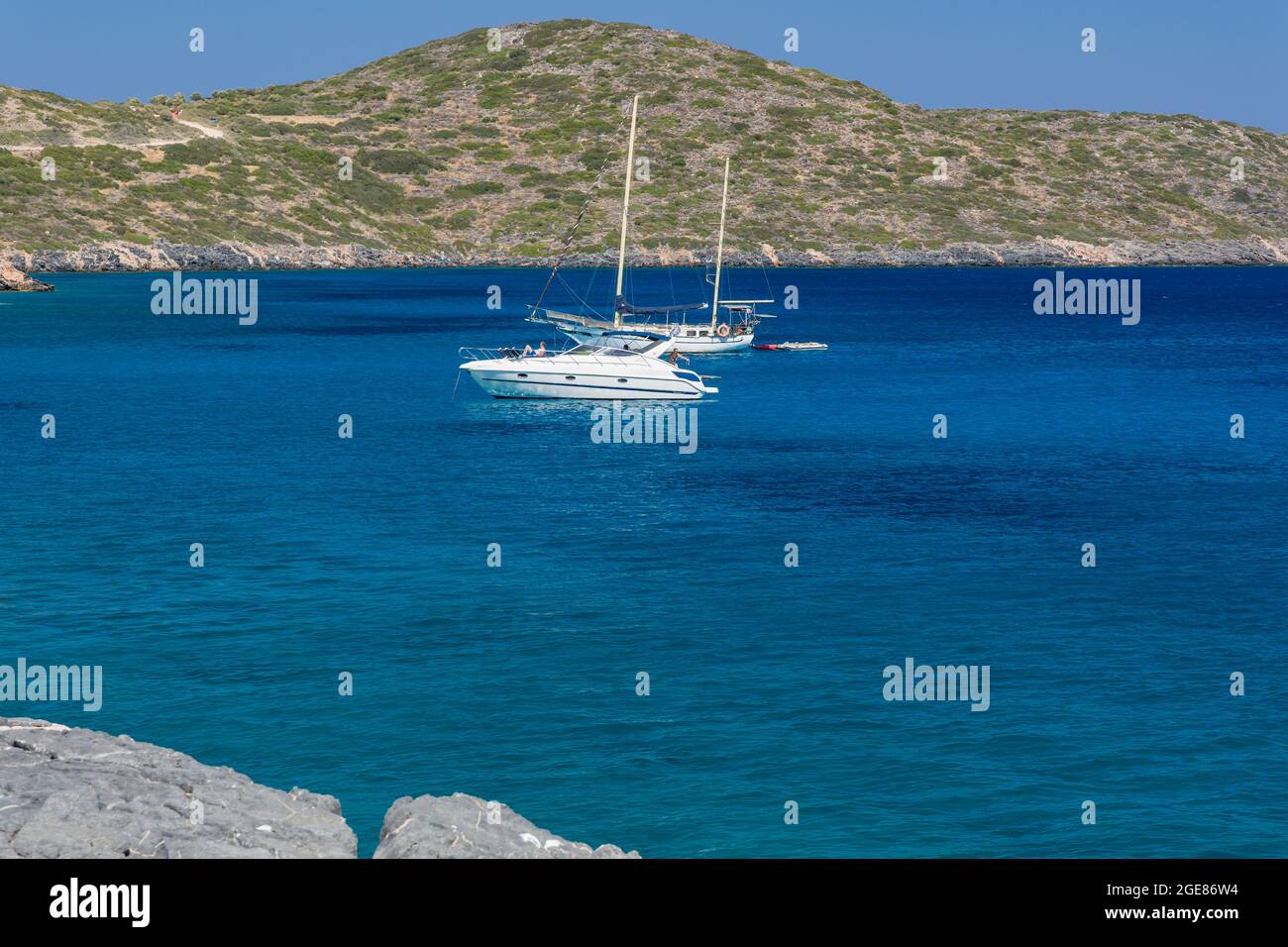 ELOUNDA, KRETA - 11. JULI 2021: Klares Wasser und trockenes Gestrüpp an der Küste in der Nähe der Stadt Elounda, Kreta, Griechenland Stockfoto