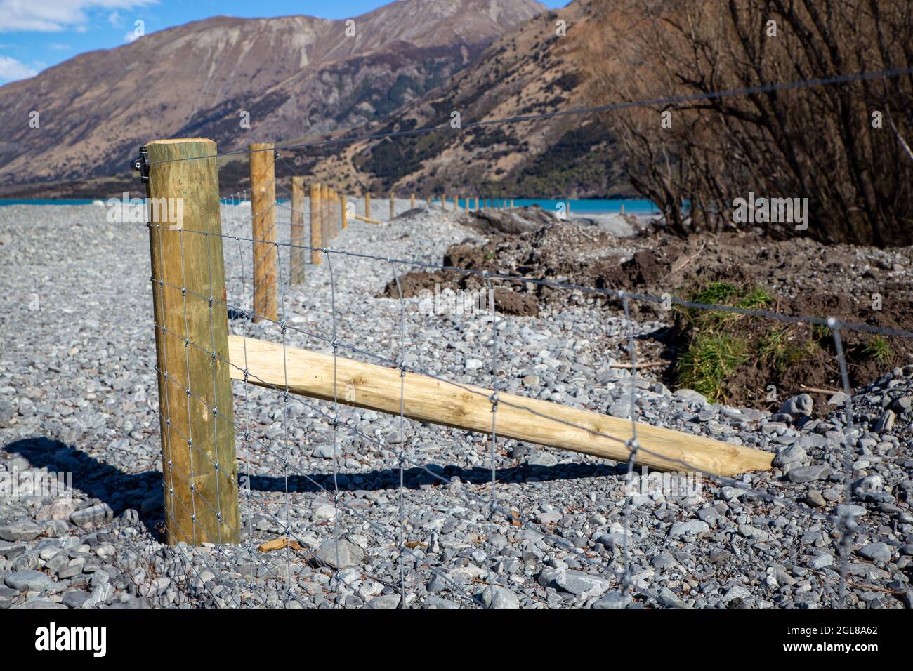 Neuer Pfosten- und Gitterzaun, der die Farmgrenze vom Flussbett im Hochland von Canterbury, Neuseeland, trennt Stockfoto