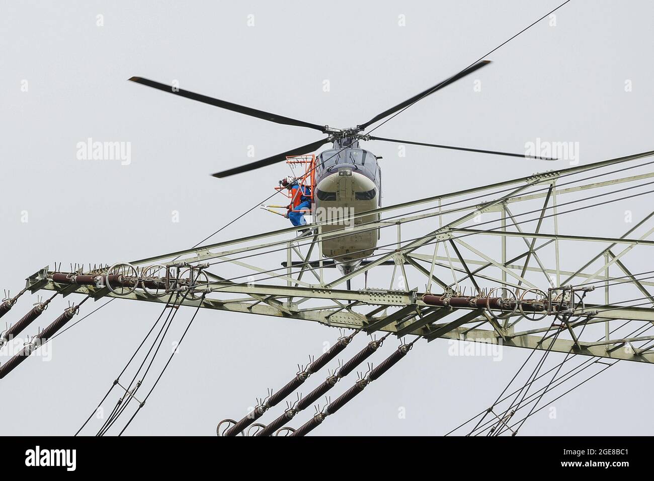 Vogelschutzmarkierungen mit Hilfe eines Hubschraubers und eines außerhalb von Deutschland sitzenden Monteers auf einer Hochspannungsleitung platzieren, Affoldern, 2017-04-10. Stockfoto