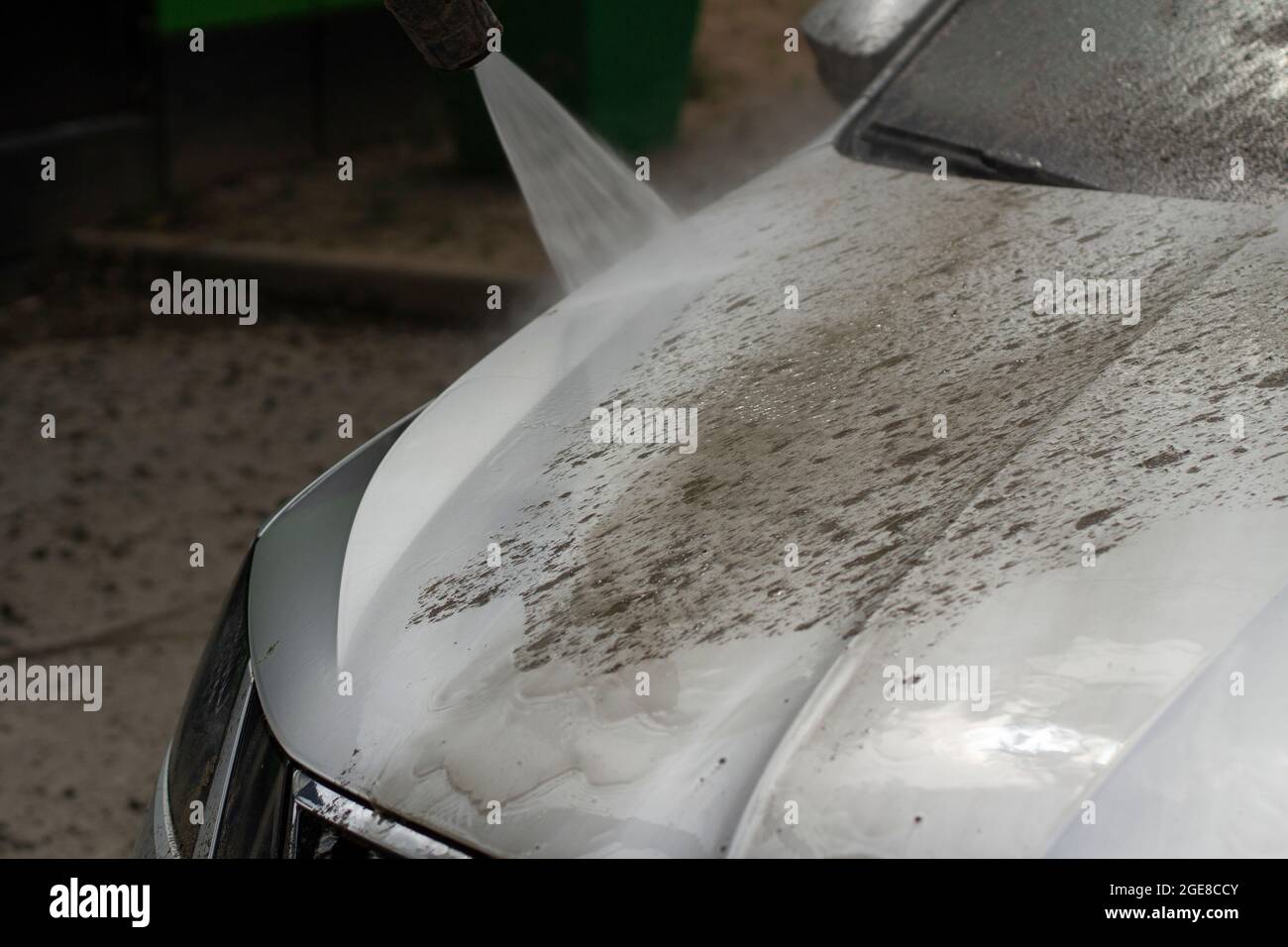 Autowäsche. Das Auto wird unter dem Druck eines Wasserstrahls gewaschen. Mit einem Wasserspray Schmutz von der Fahrzeugoberfläche abwaschen. Stockfoto