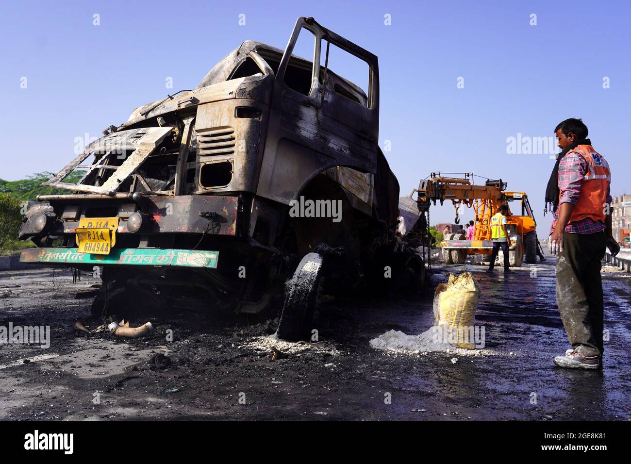 Nicht exklusiv: Ein Arbeiter wird gesehen, wie er den LKW überprüft, der nach dem Unfall beschädigt wurde. Ein Feuer bricht aus nach einer Kollision zwischen zwei LKWs auf einem Nat Stockfoto