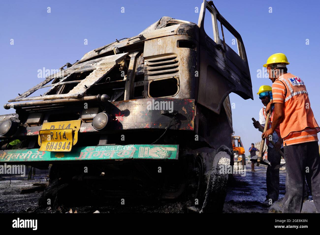 Nicht exklusiv: Ein Arbeiter wird gesehen, wie er den LKW überprüft, der nach dem Unfall beschädigt wurde. Ein Feuer bricht aus nach einer Kollision zwischen zwei LKWs auf einem Nat Stockfoto