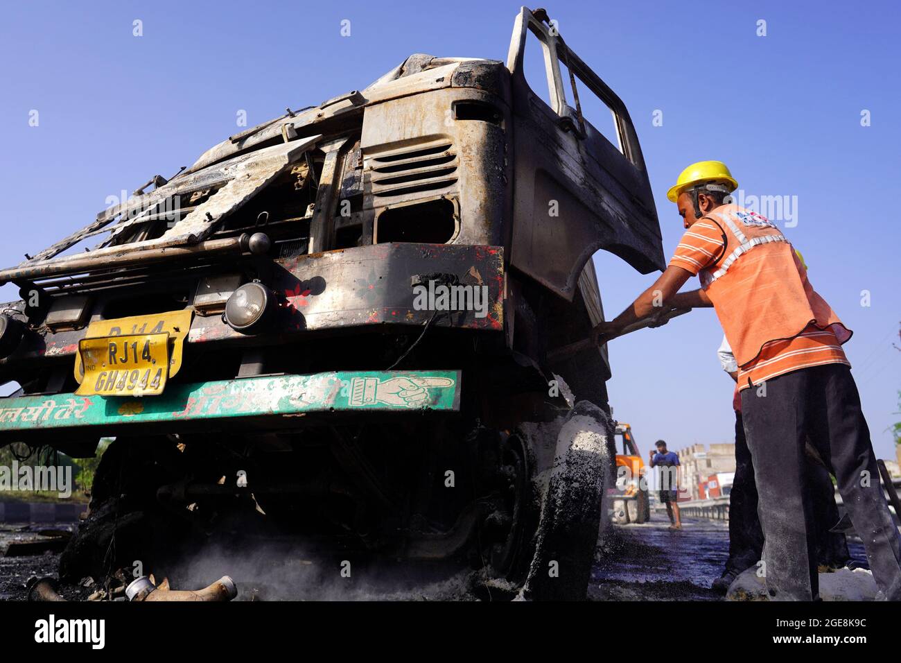 Nicht exklusiv: Ein Arbeiter wird gesehen, wie er den LKW überprüft, der nach dem Unfall beschädigt wurde. Ein Feuer bricht aus nach einer Kollision zwischen zwei LKWs auf einem Nat Stockfoto