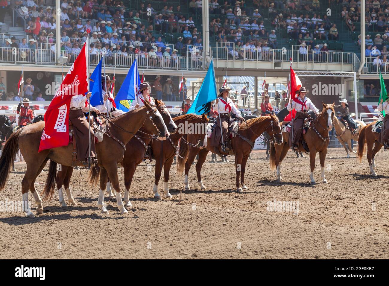 Jockeys in roter Uniform stehen bei der Hundertjahrfeier der Calgary Stampede in Alberta mit ihren Pferden auf. Stockfoto
